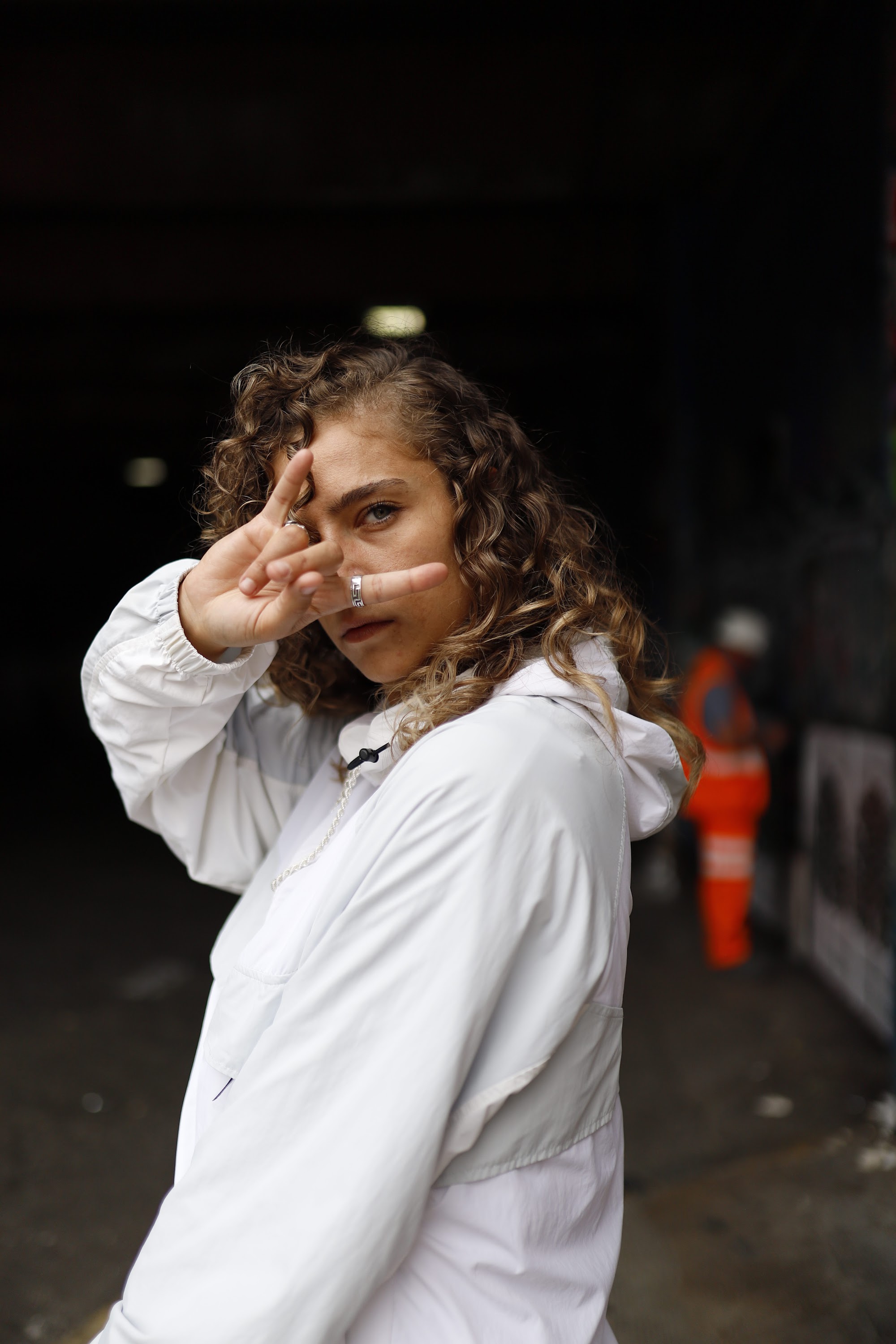 Woman in White Jacket Holding Sunglasses – Dark Urban Tunnel