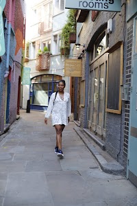 Woman in White Lace-Up Tunic with Raised Hands on Urban Street