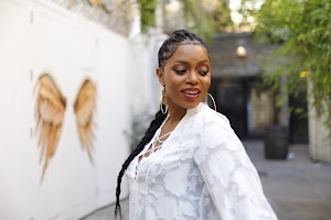 Woman in White Lace-Up Tunic with Raised Hands on Urban Street