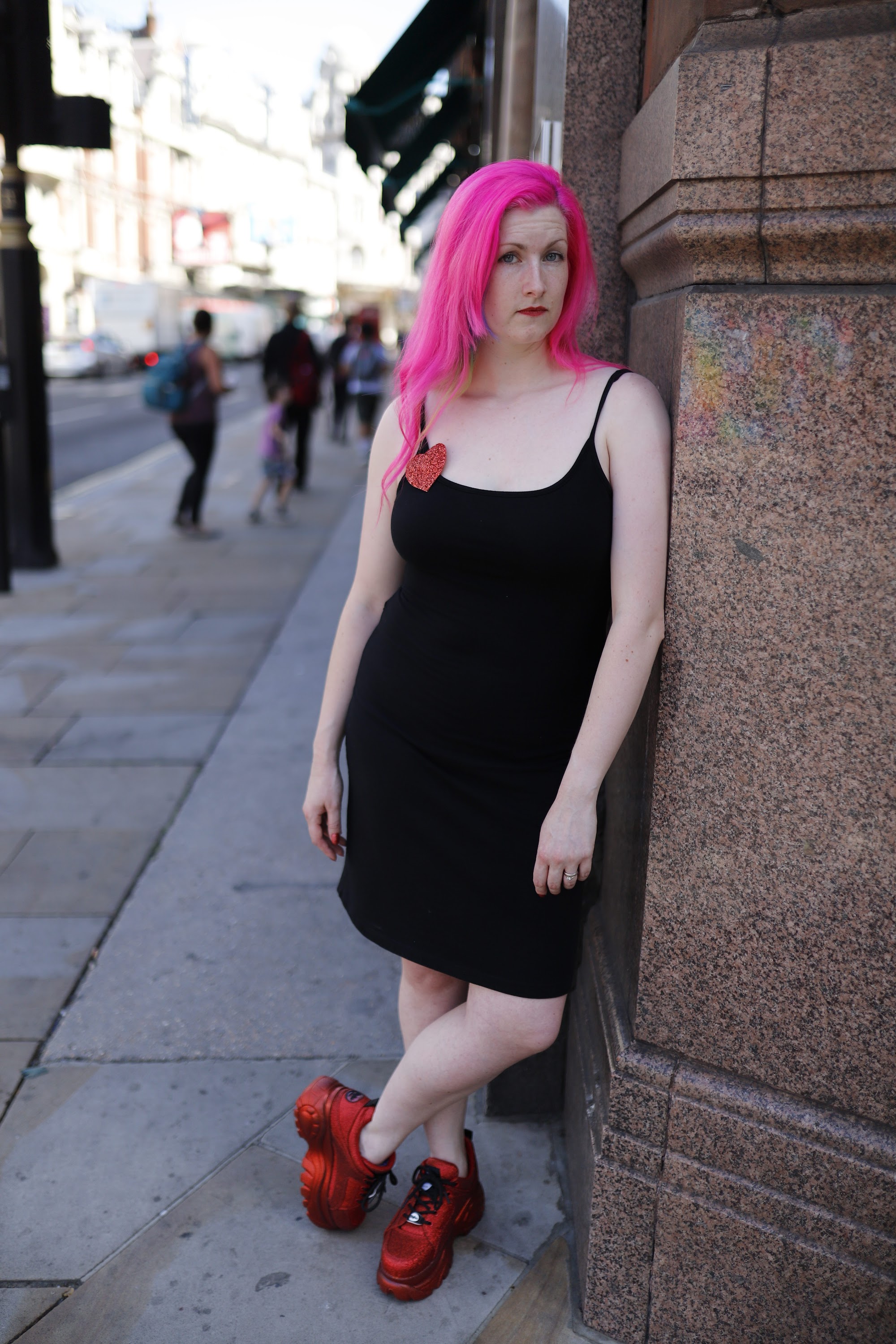 Woman with Pink Hair Leaning Against Tiled Wall in Indoor Corridor
