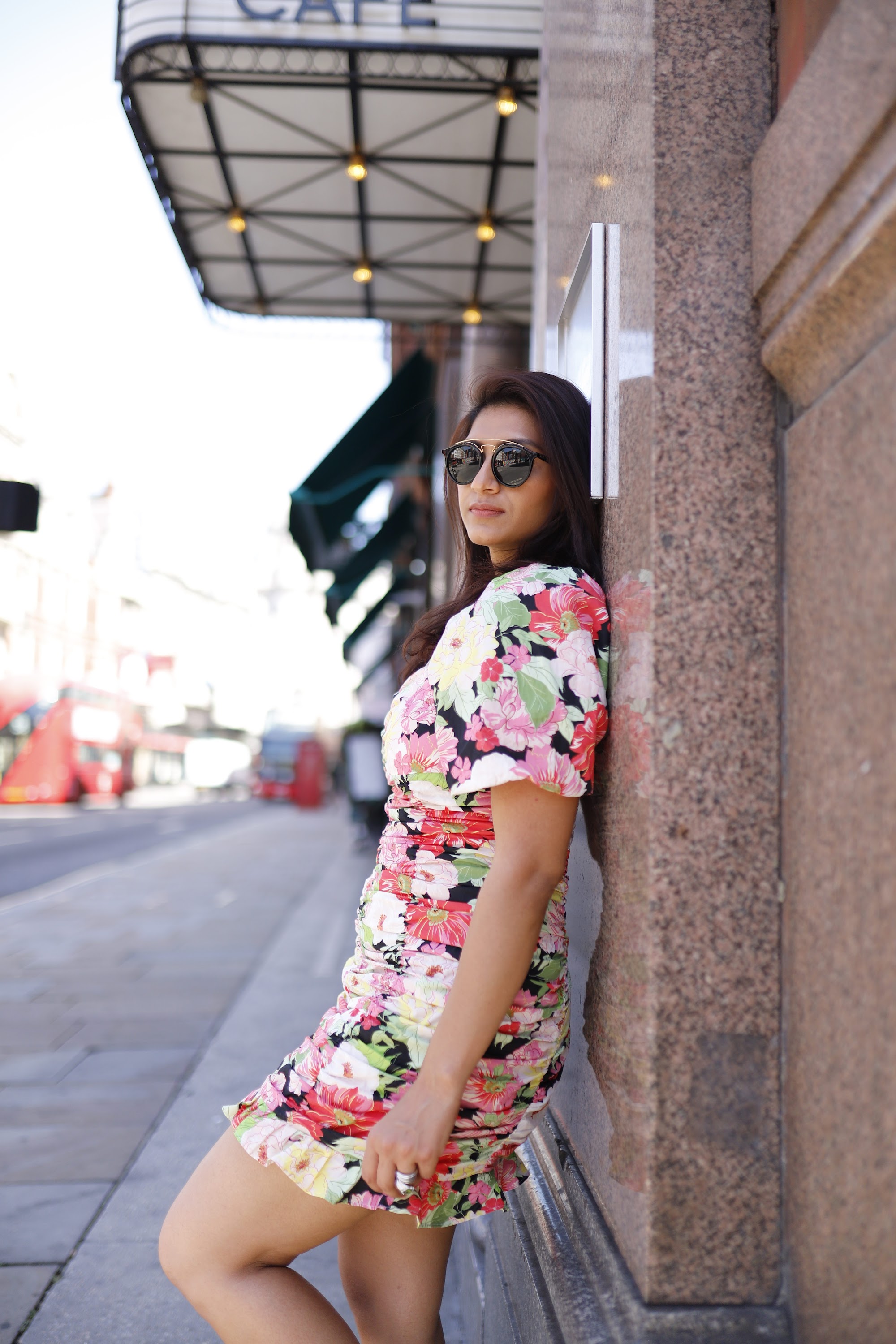 Woman in Floral Dress Leaning Against Stone Column on European City Street