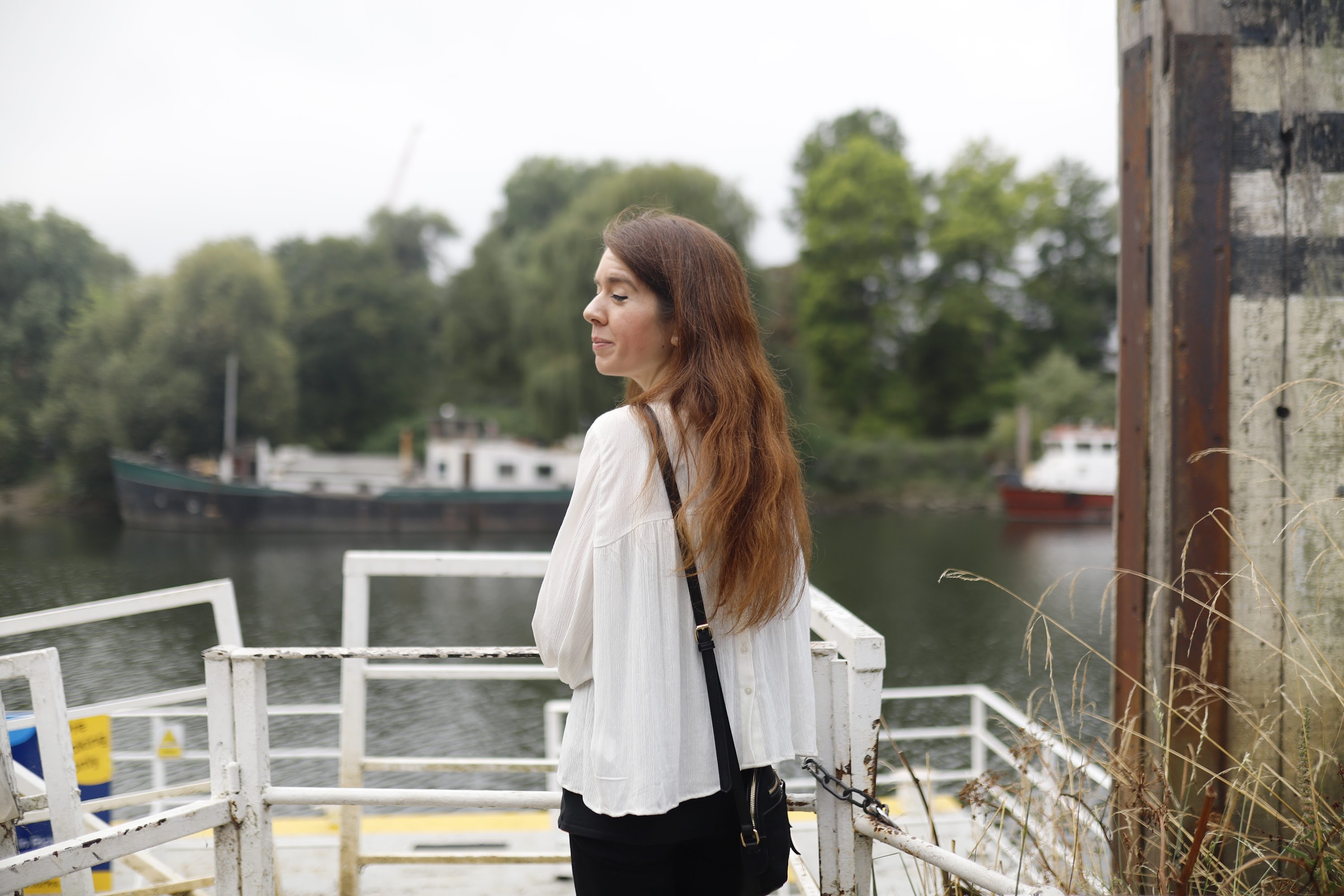 Young Woman Posing by Riverside Railing