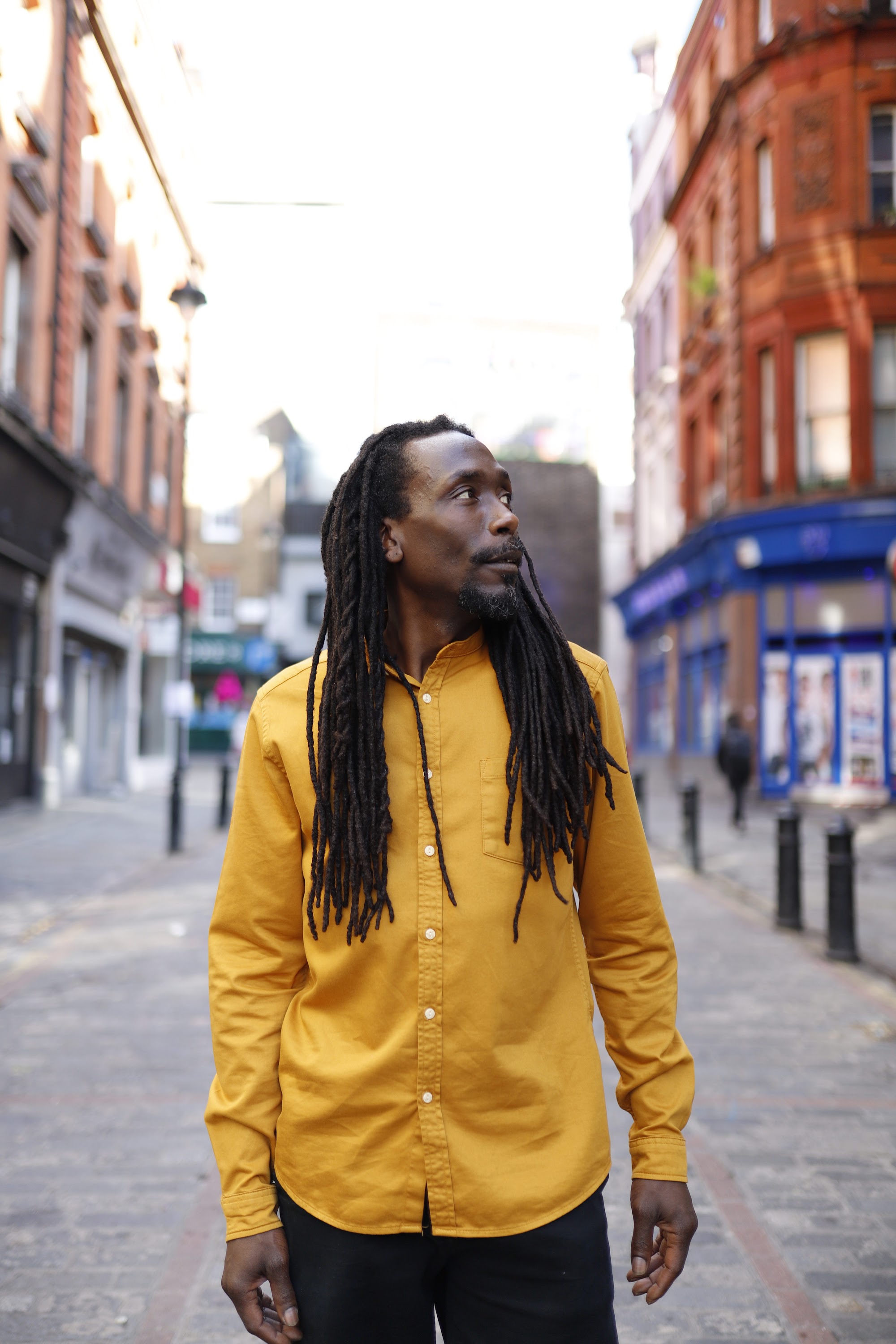 Man in Yellow Shirt on Cobblestone City Street