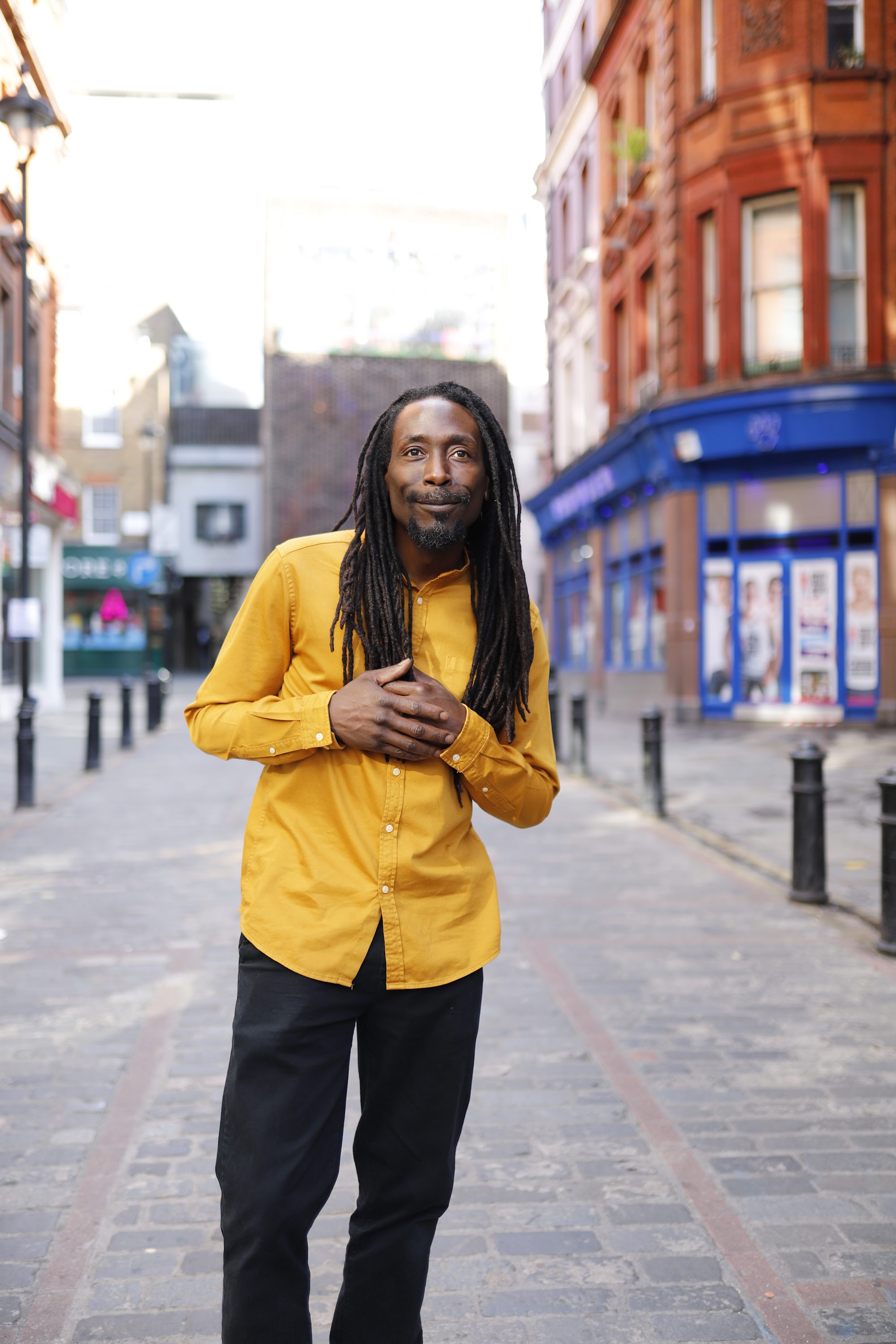 Man in Yellow Shirt on Cobblestone City Street
