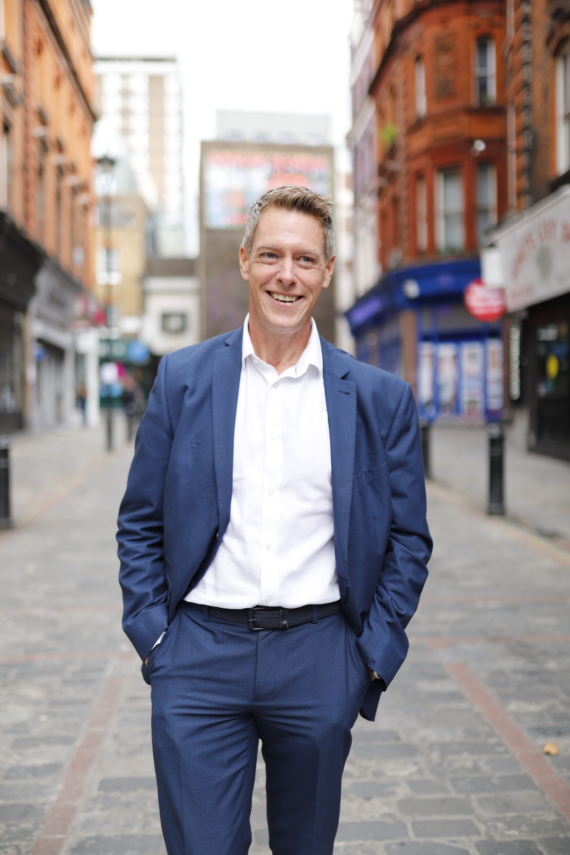 Man in Navy Suit on Cobblestone Urban Street