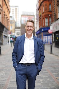 Man in Navy Suit on Cobblestone Urban Street
