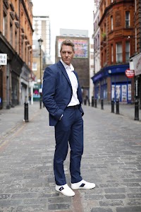 Man in Navy Suit on Cobblestone Urban Street
