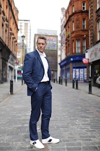 Man in Navy Suit on Cobblestone Urban Street