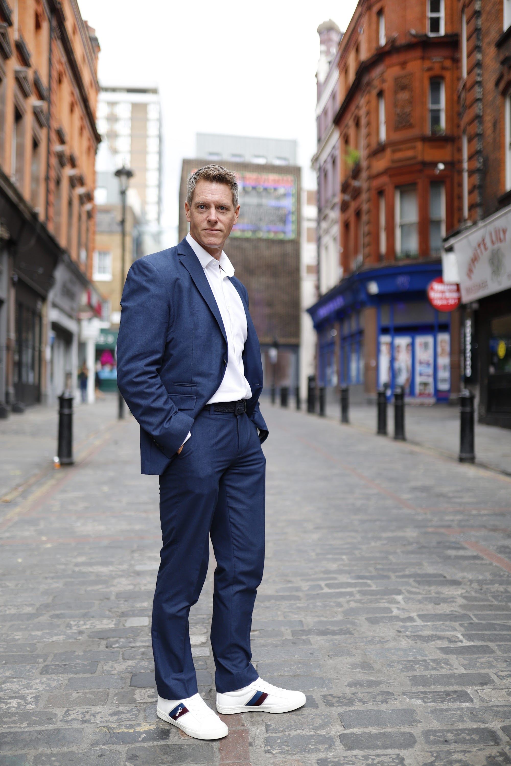 Man in Navy Suit on Cobblestone Urban Street