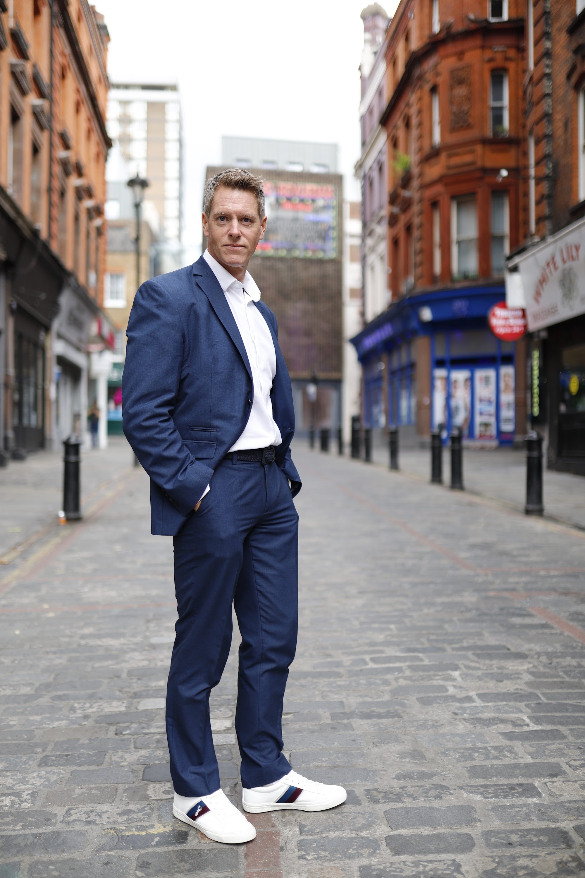 Man in Navy Suit on Cobblestone Urban Street