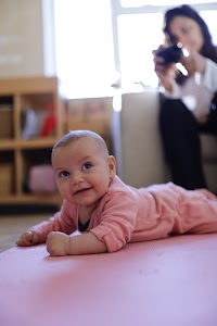 Baby Lying on Pink Mat While Woman Takes Photo
