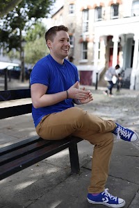 Young Man Laughing on Urban Park Bench