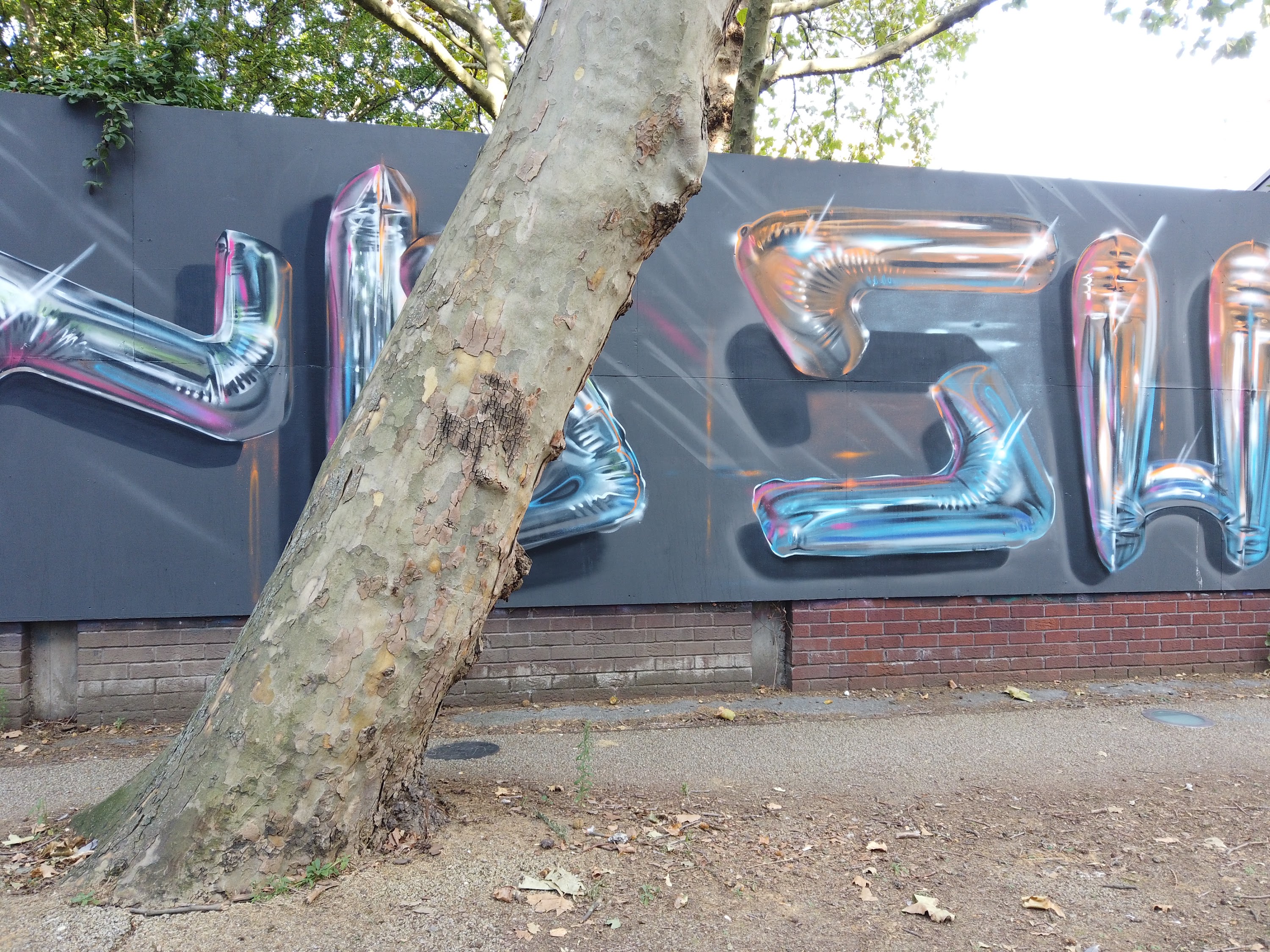 Chrome Balloon-Style Graffiti Mural on Gray Hoarding Wall