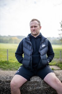 Young Man in Nike Athletic Wear Seated on Stone Wall at Misty Park