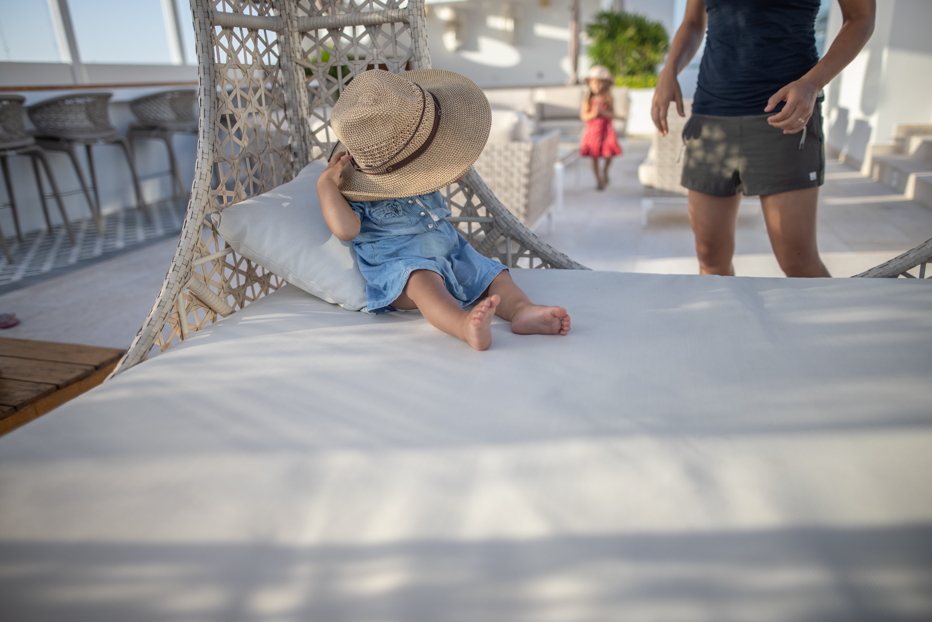 Child Hiding Behind Hat on Outdoor Daybed
