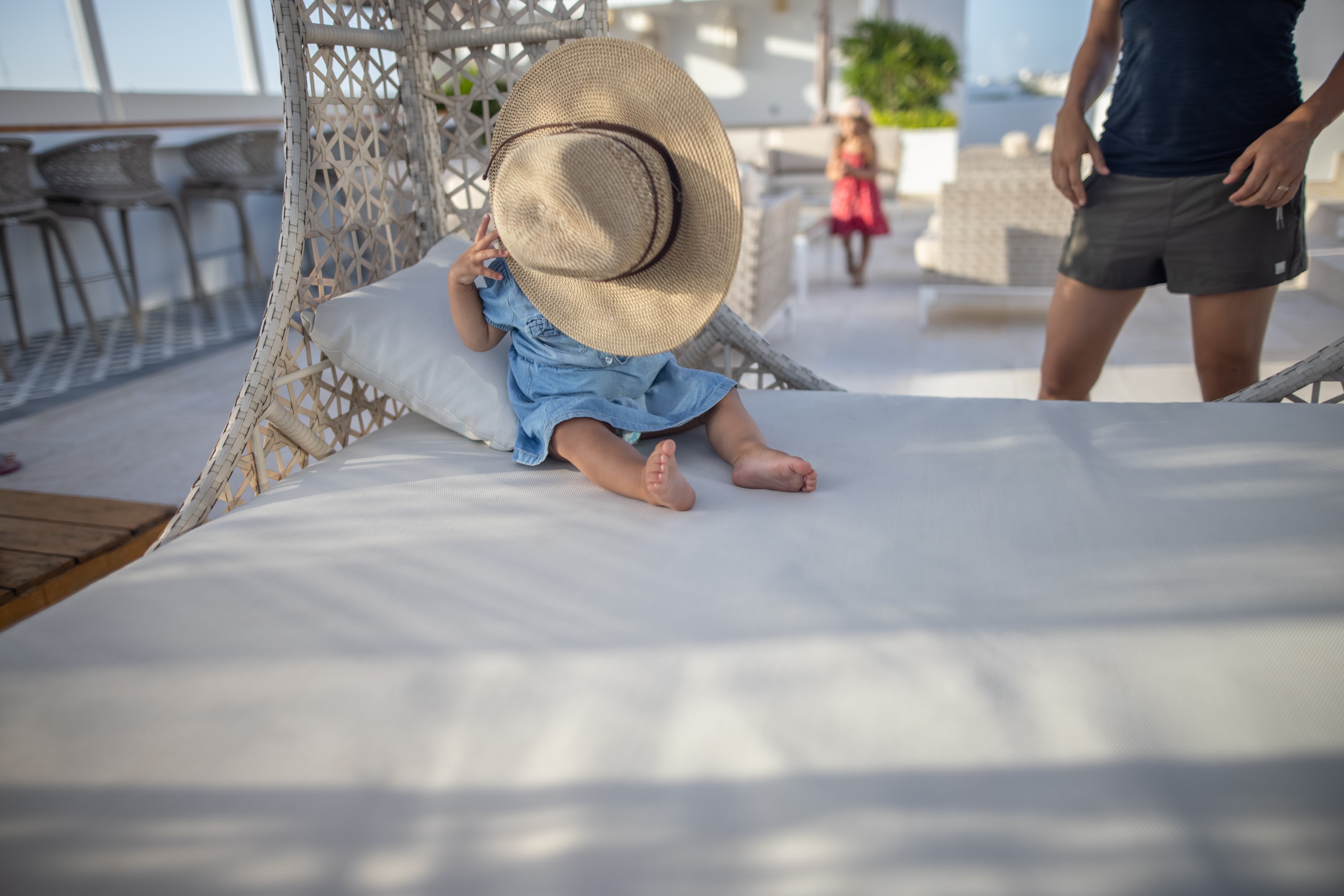 Child Hiding Behind a Straw Hat on Outdoor Lounger
