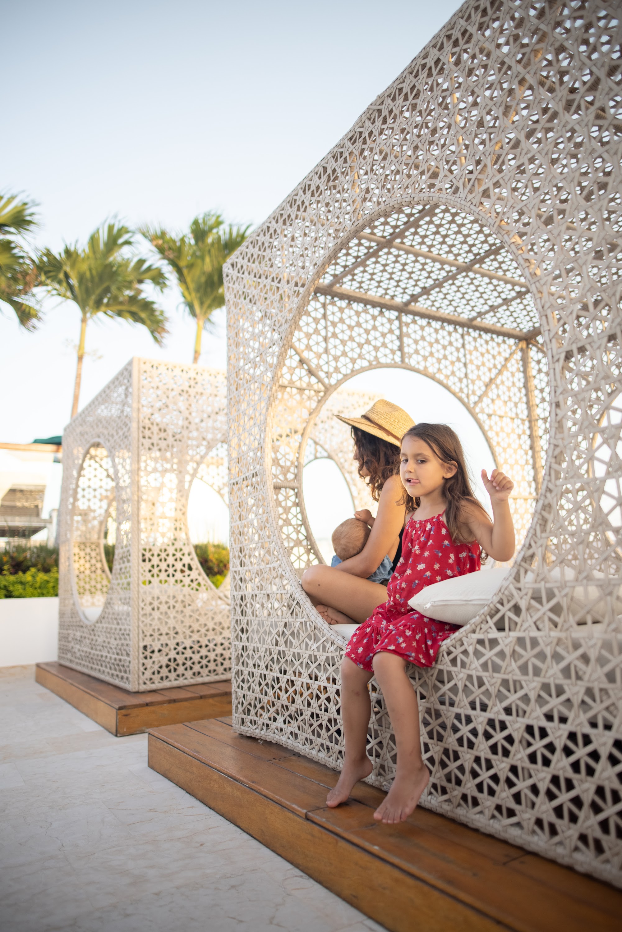 Mother and daughter relaxing in white wicker lounge chairs at tropical resort