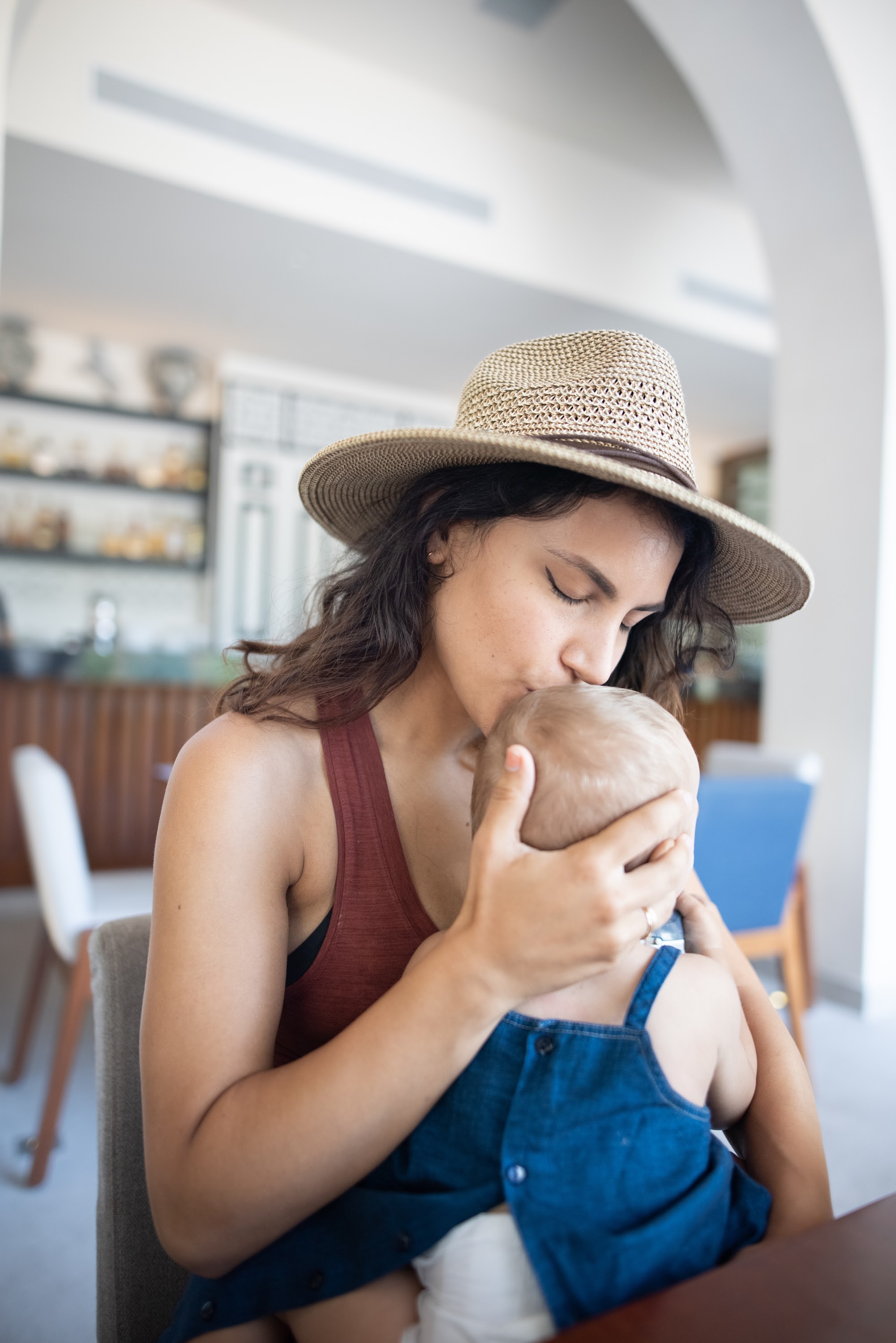 Mother Kisses Baby's Head While Wearing Straw Hat