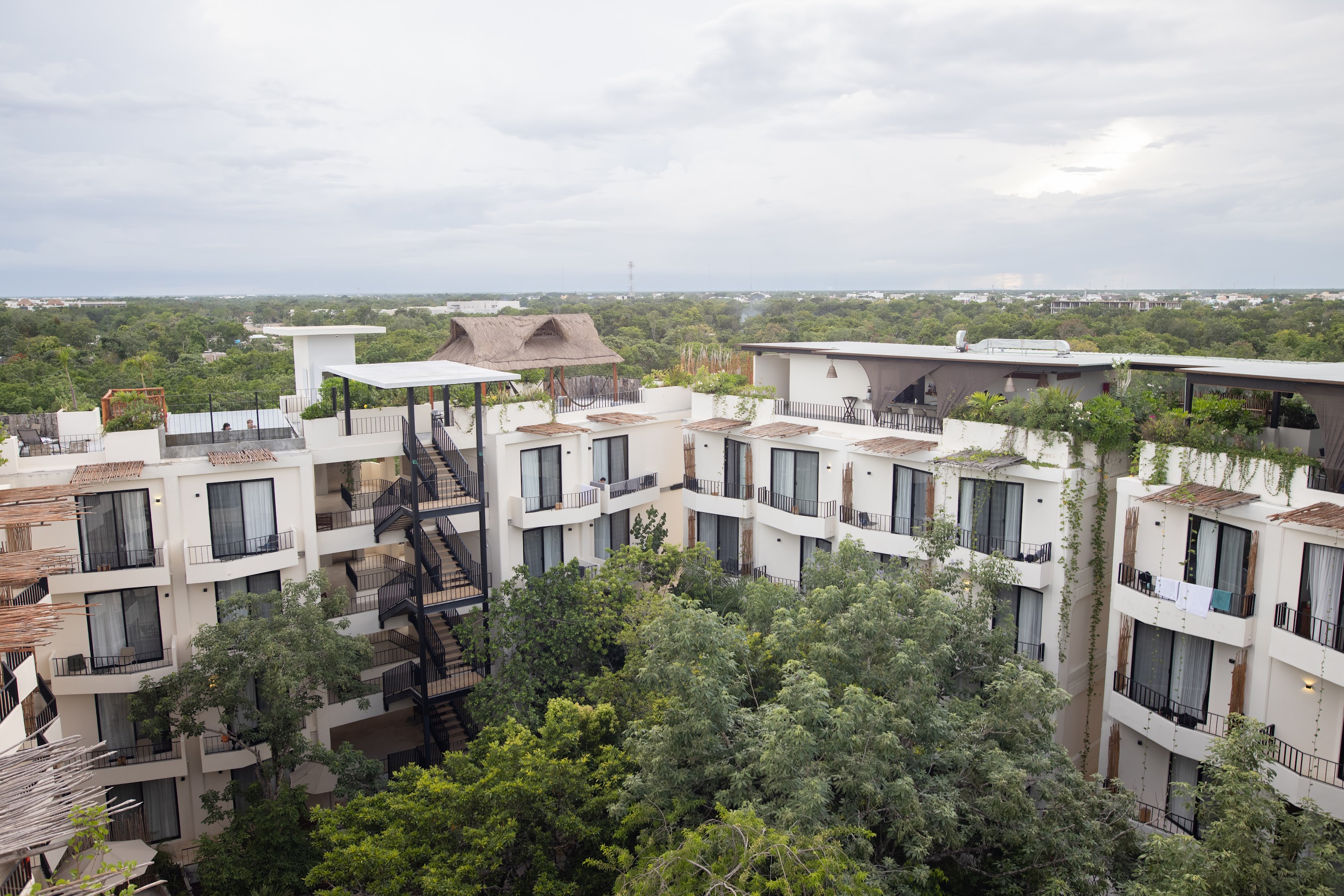 Modern White Apartment Complex with Greenery and Rooftop Terraces