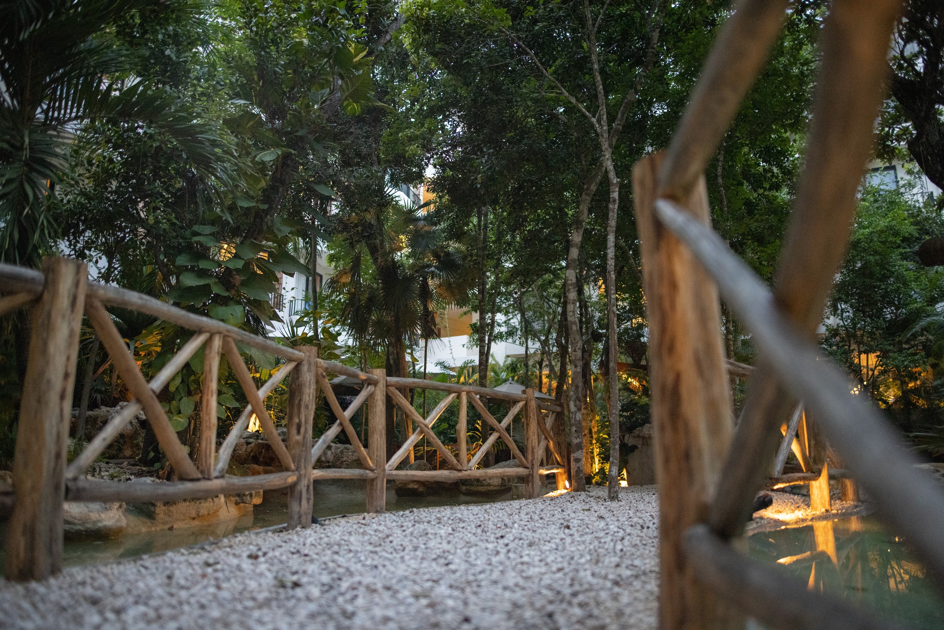 Wooden Bridge Over Pebbled Path in Lush Garden