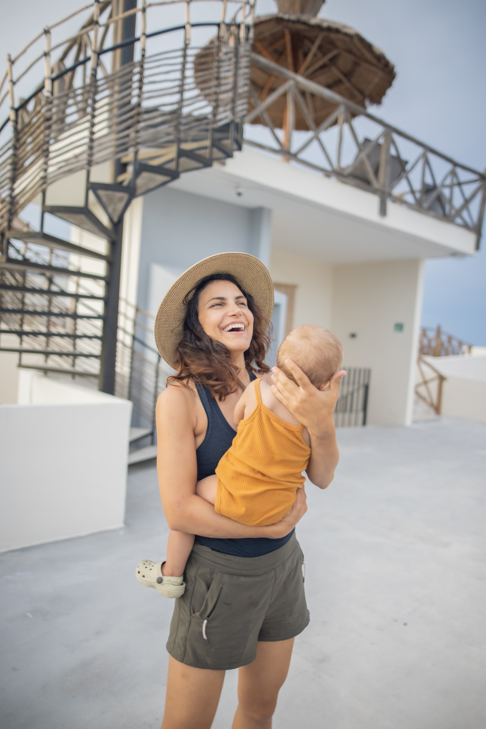 Mother Laughing While Holding Baby on Rooftop Terrace