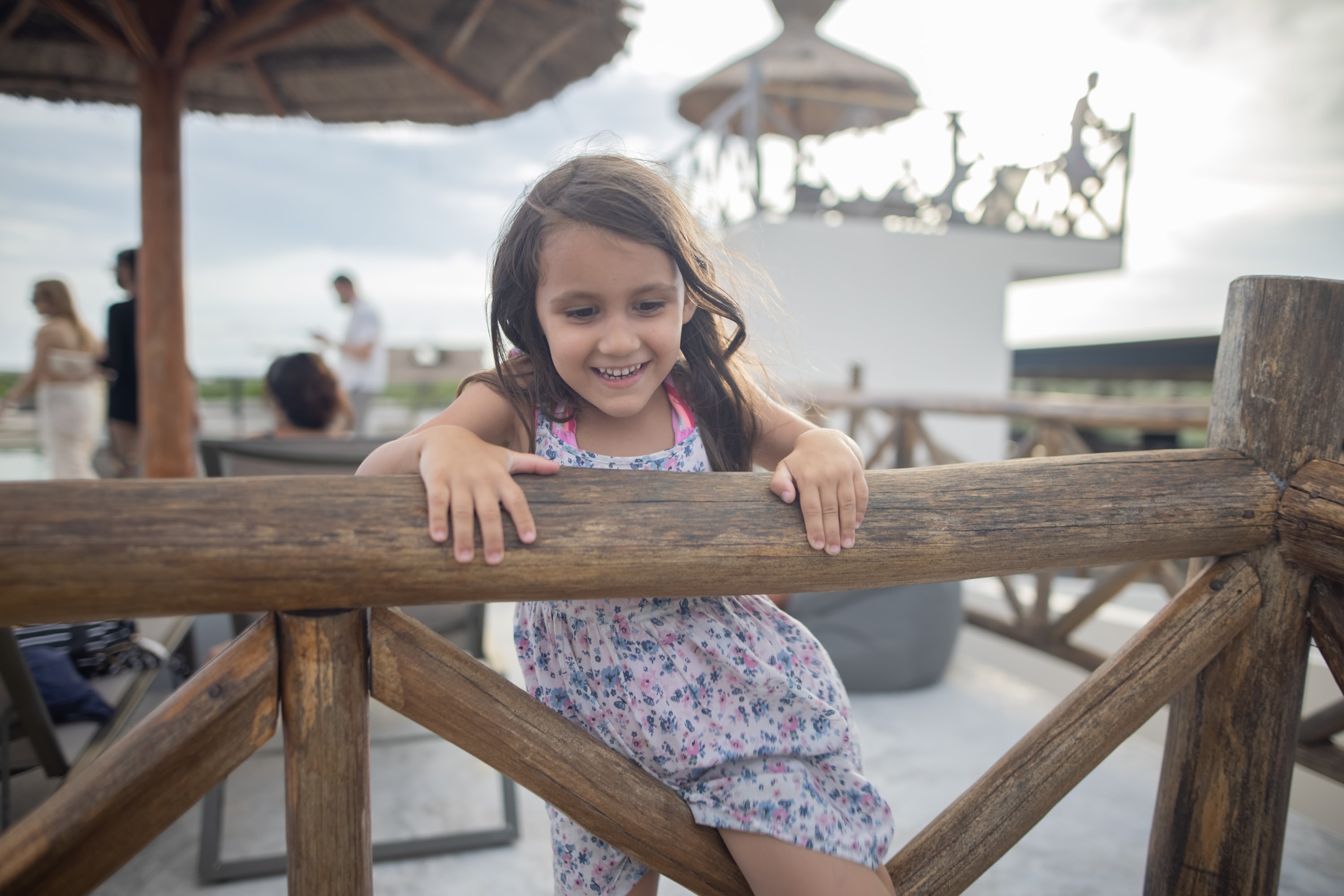 Smiling Girl Leaning on Wooden Fence at Outdoor Terrace