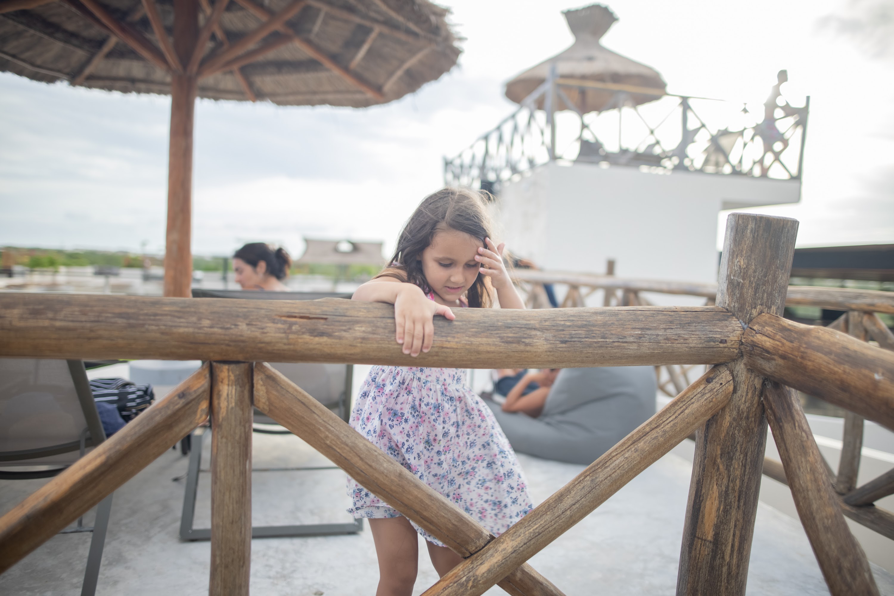 Girl Leaning on Wooden Railing at Rooftop Terrace