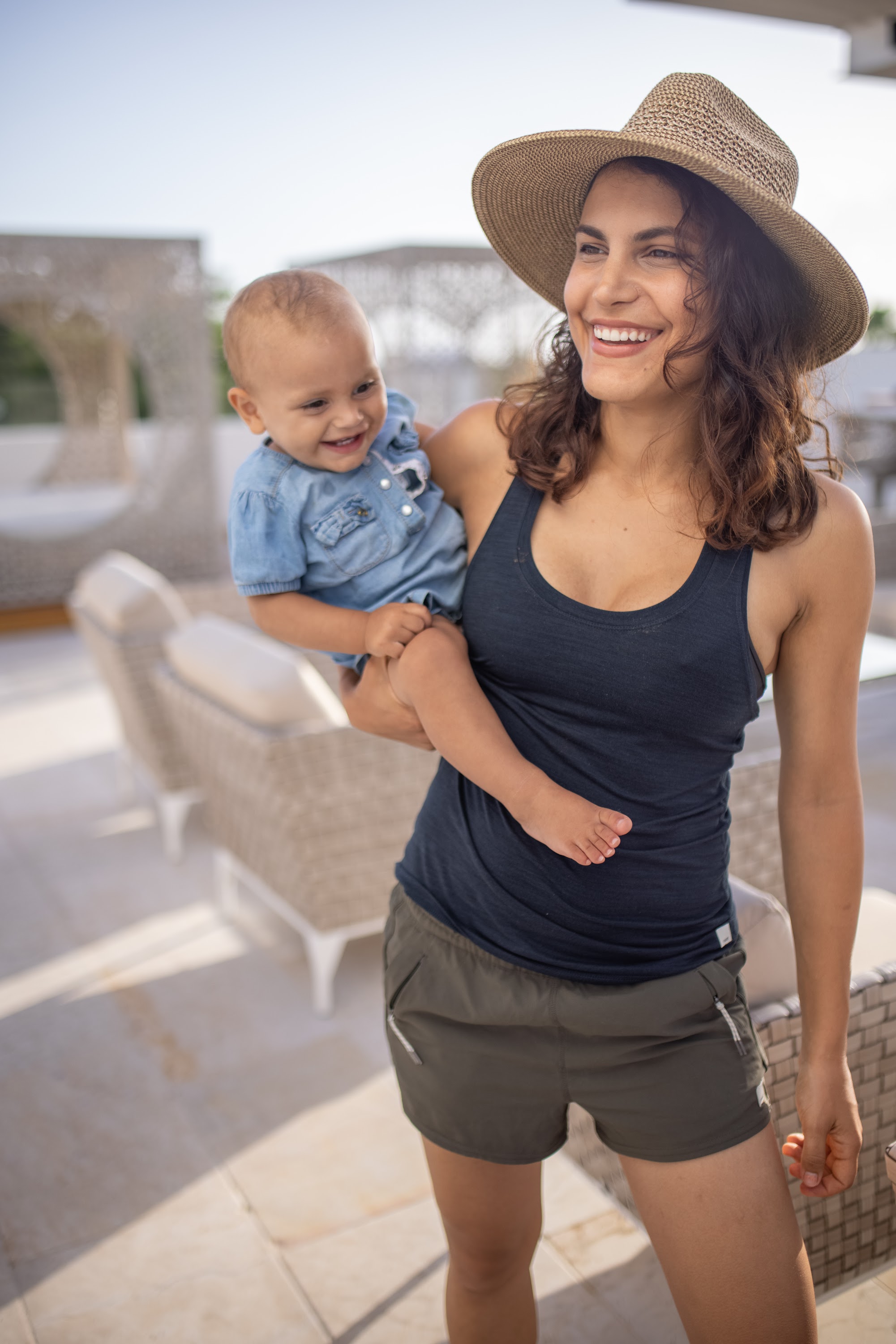 Smiling Mother Holding Baby on Sunlit Terrace