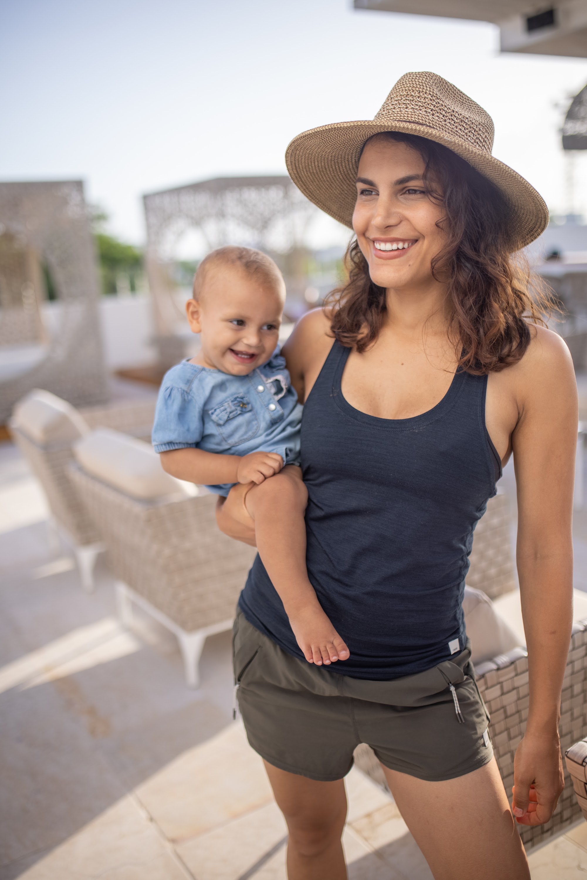 Smiling Mother Holding Baby on Sunlit Terrace