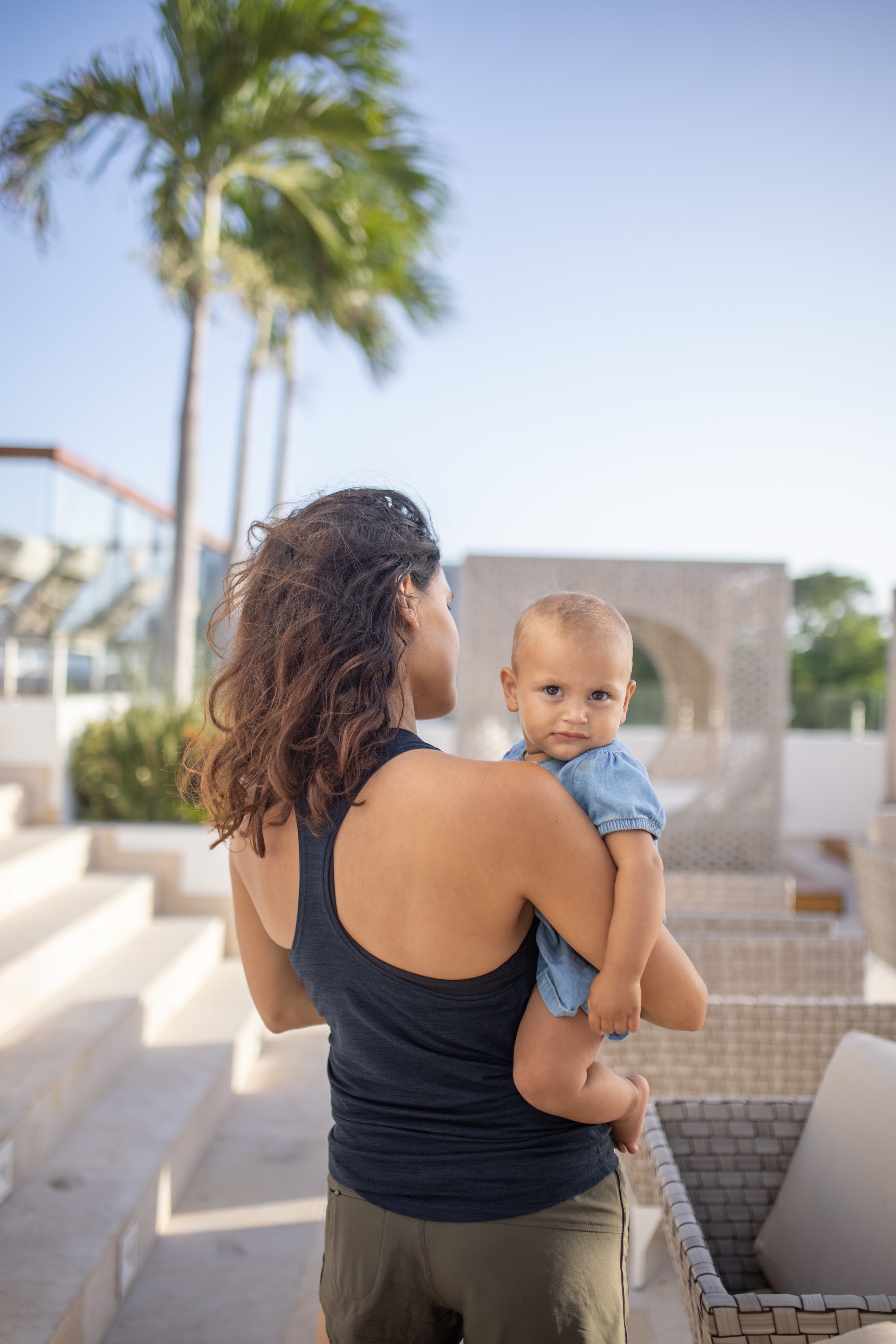 Mother Holding Baby Outdoors Near Palm Trees
