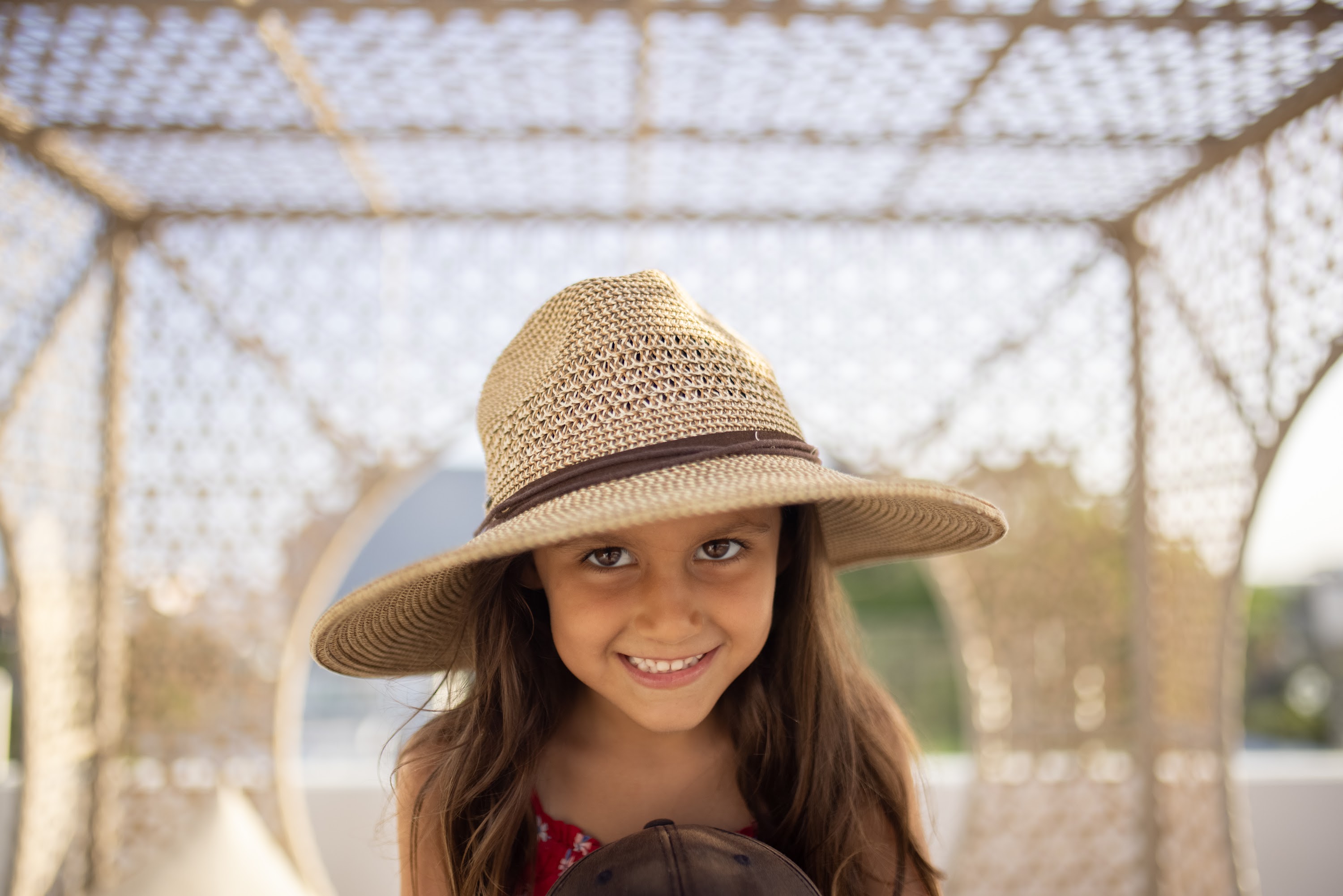 Smiling Girl in Straw Hat Under Canopy