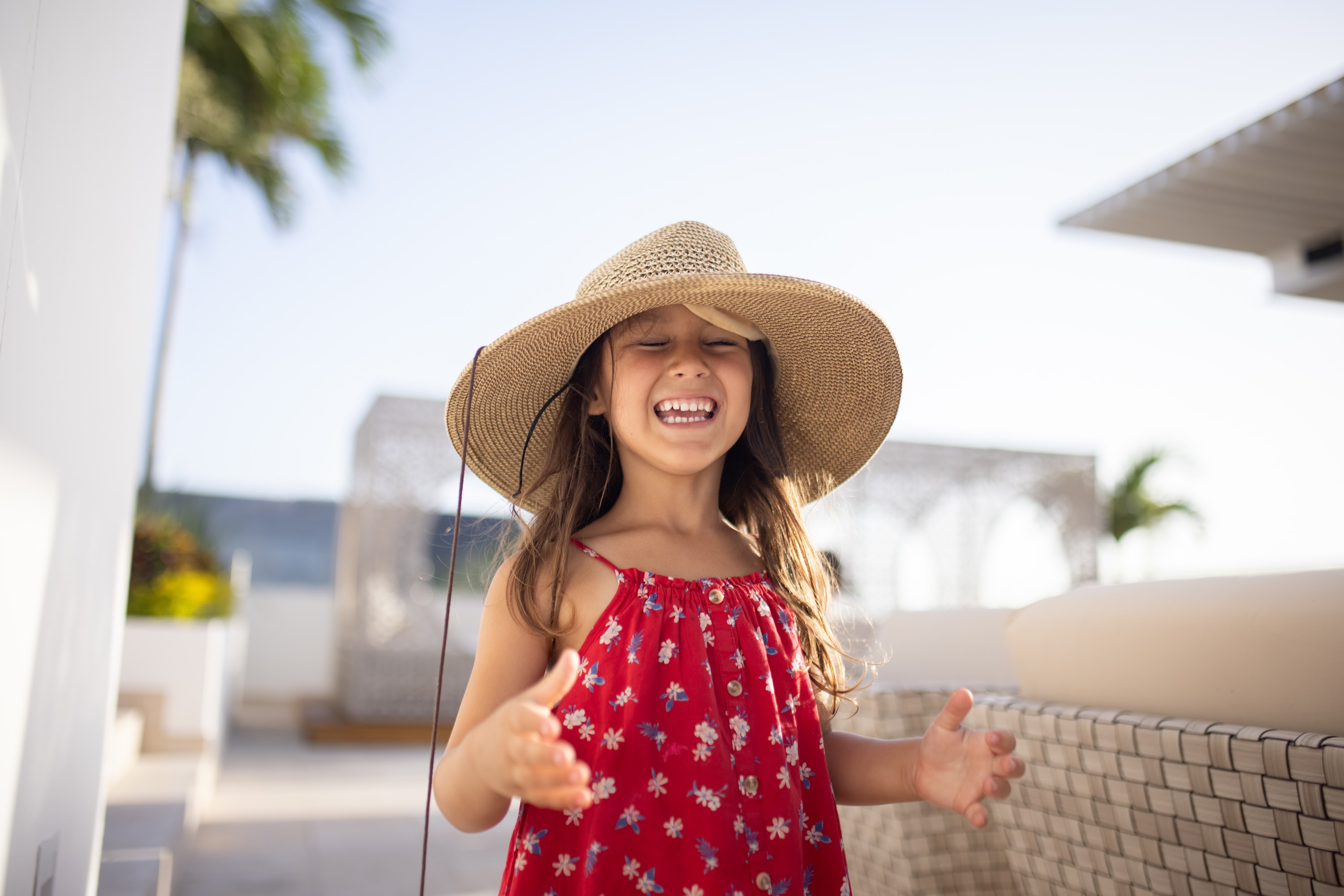 Happy Girl in Sun Hat on Balcony