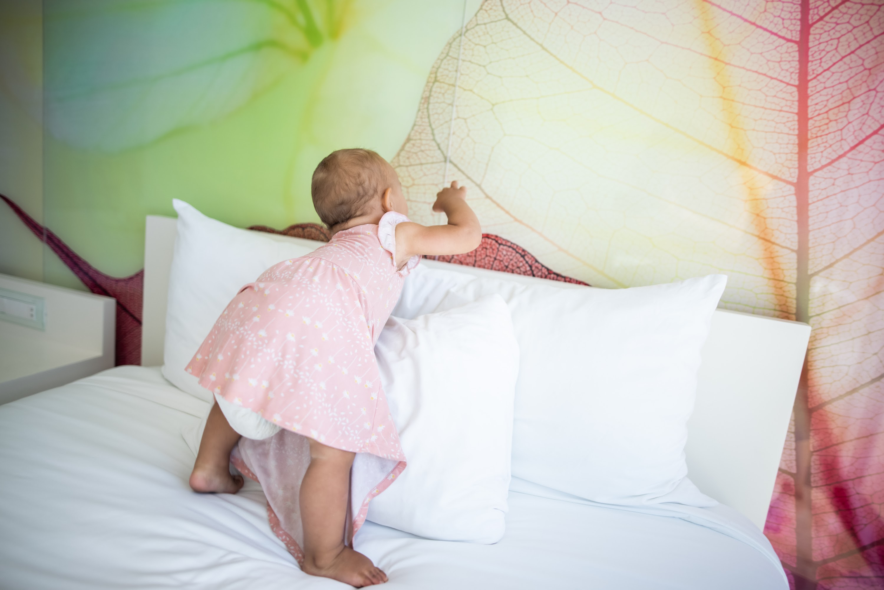 Baby in Pink Dress Climbing on Bed