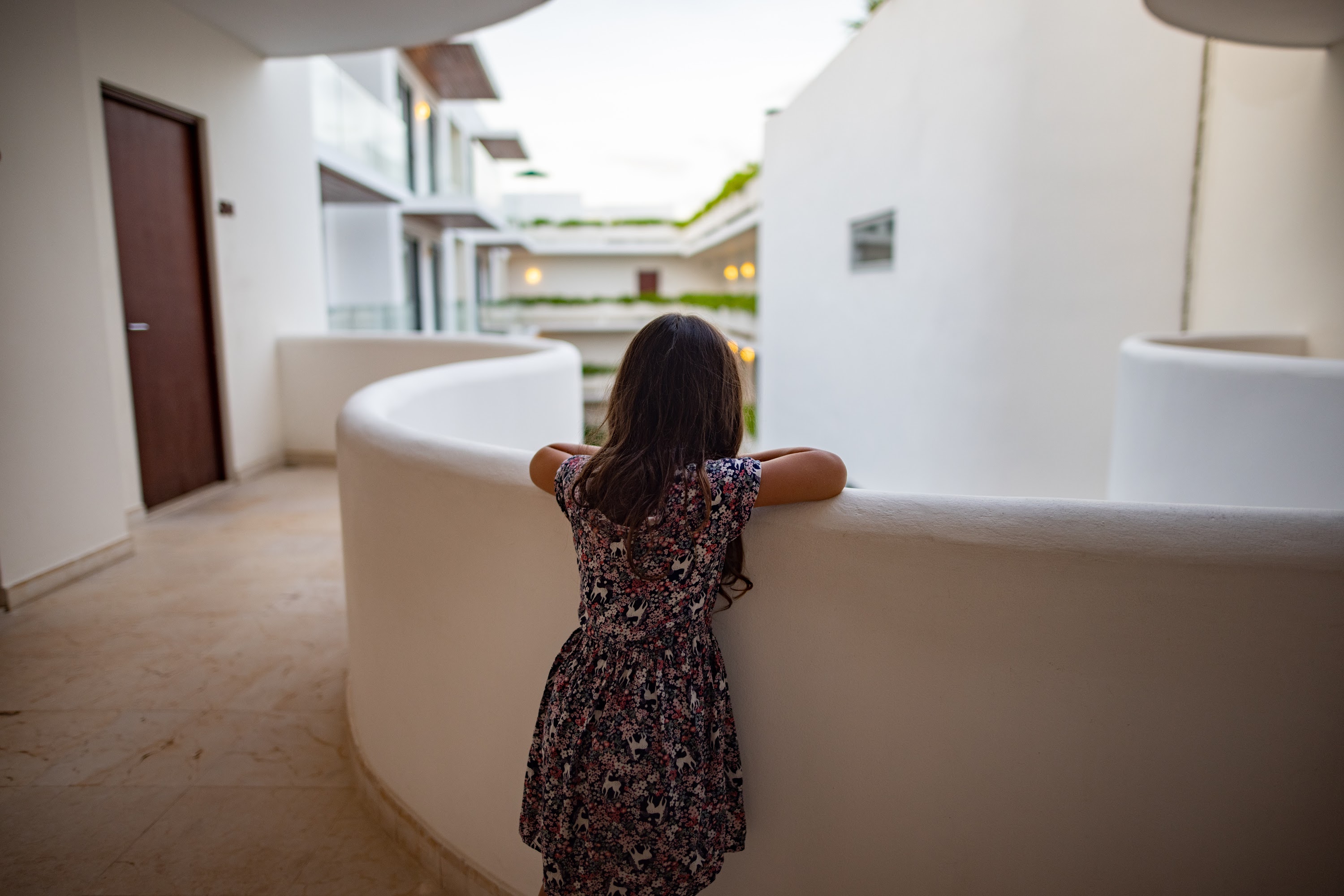Girl Leaning on White Balcony Railing