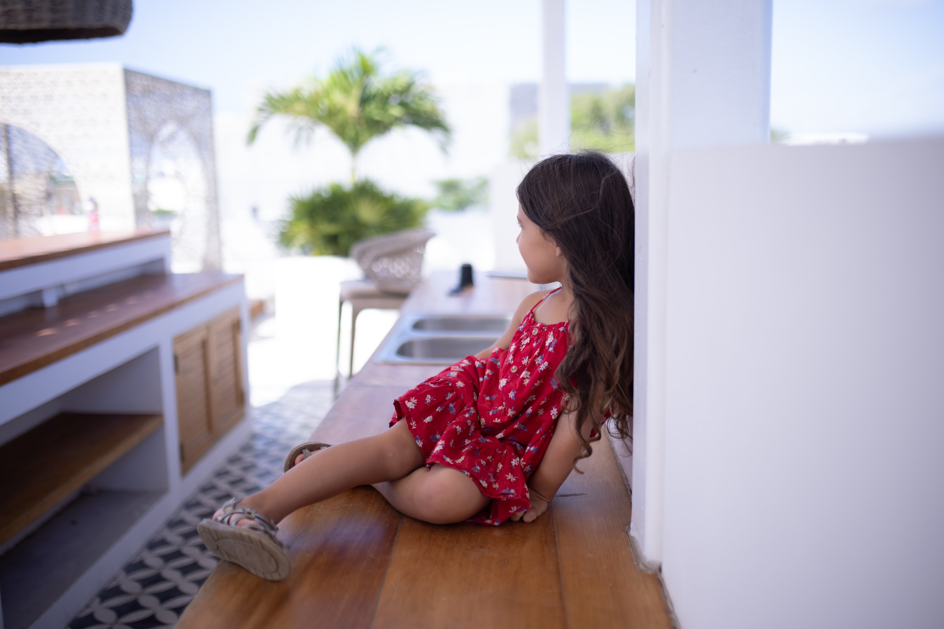 Girl in Red Dress Sitting on Outdoor Counter