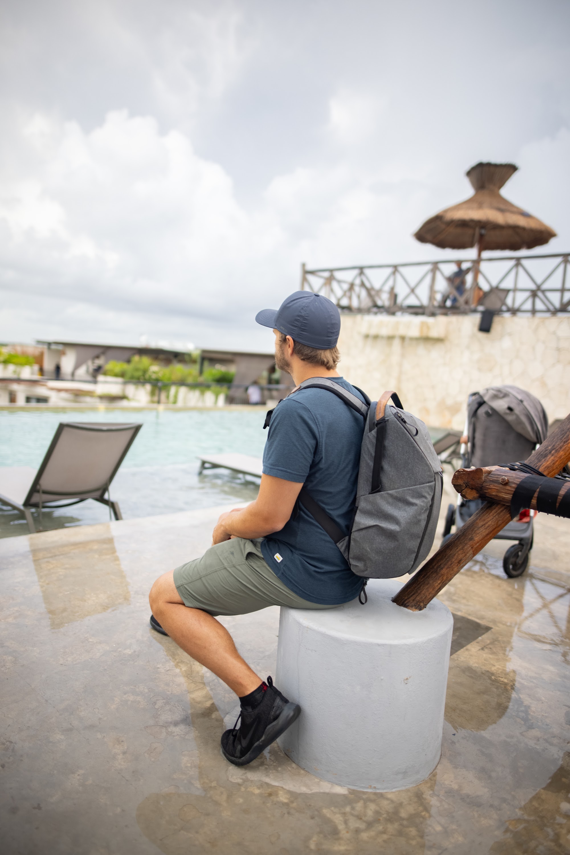 Man Sitting by Poolside with Backpack