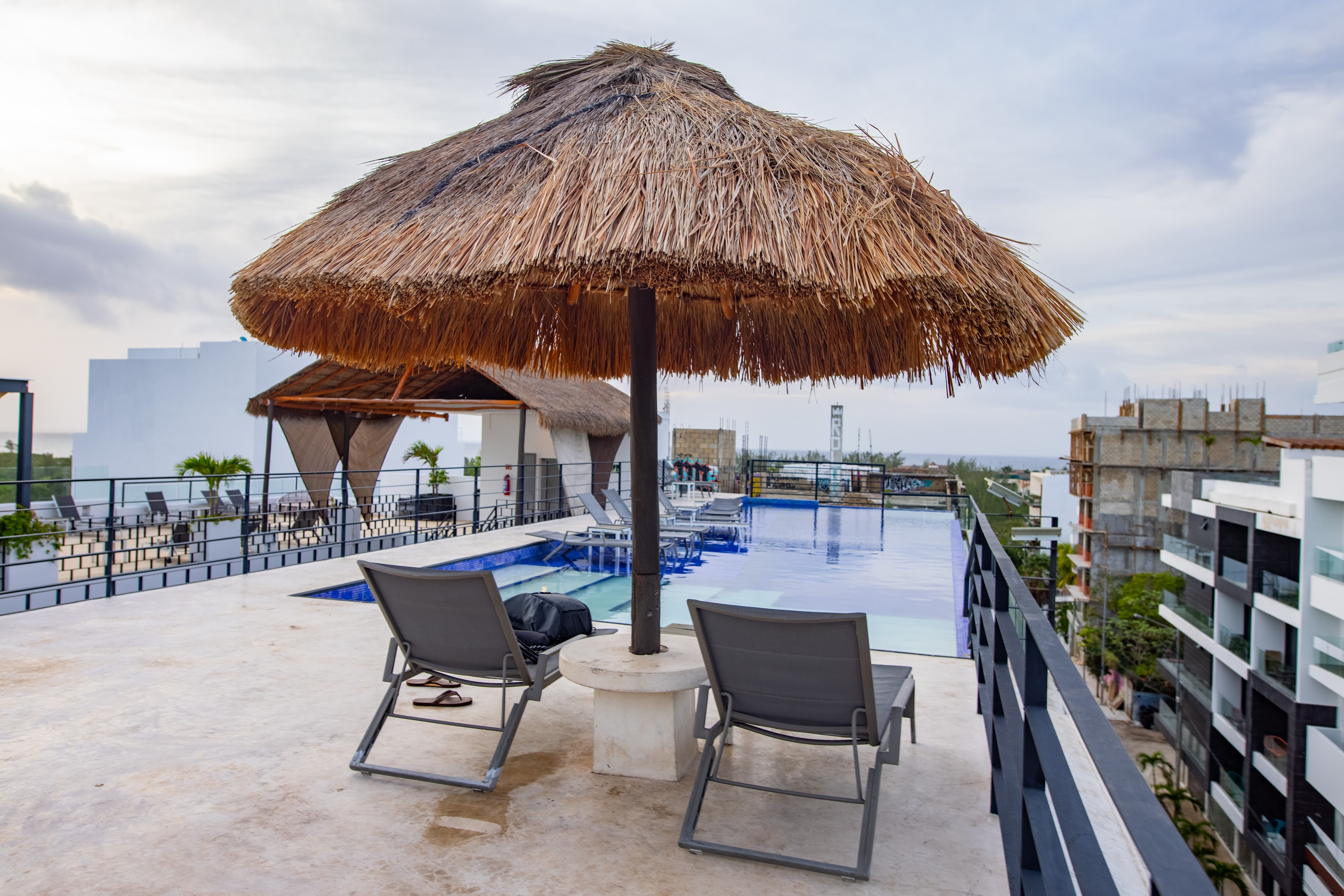 Rooftop Pool Area with Thatched Umbrella and Lounge Chairs