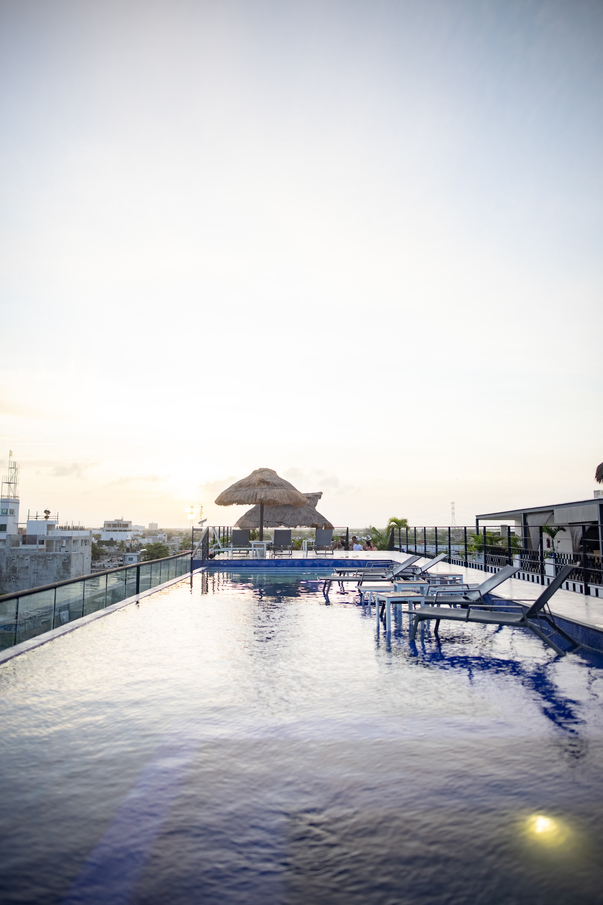Rooftop Pool at Sunset with Thatched Umbrella and Lounge Chairs
