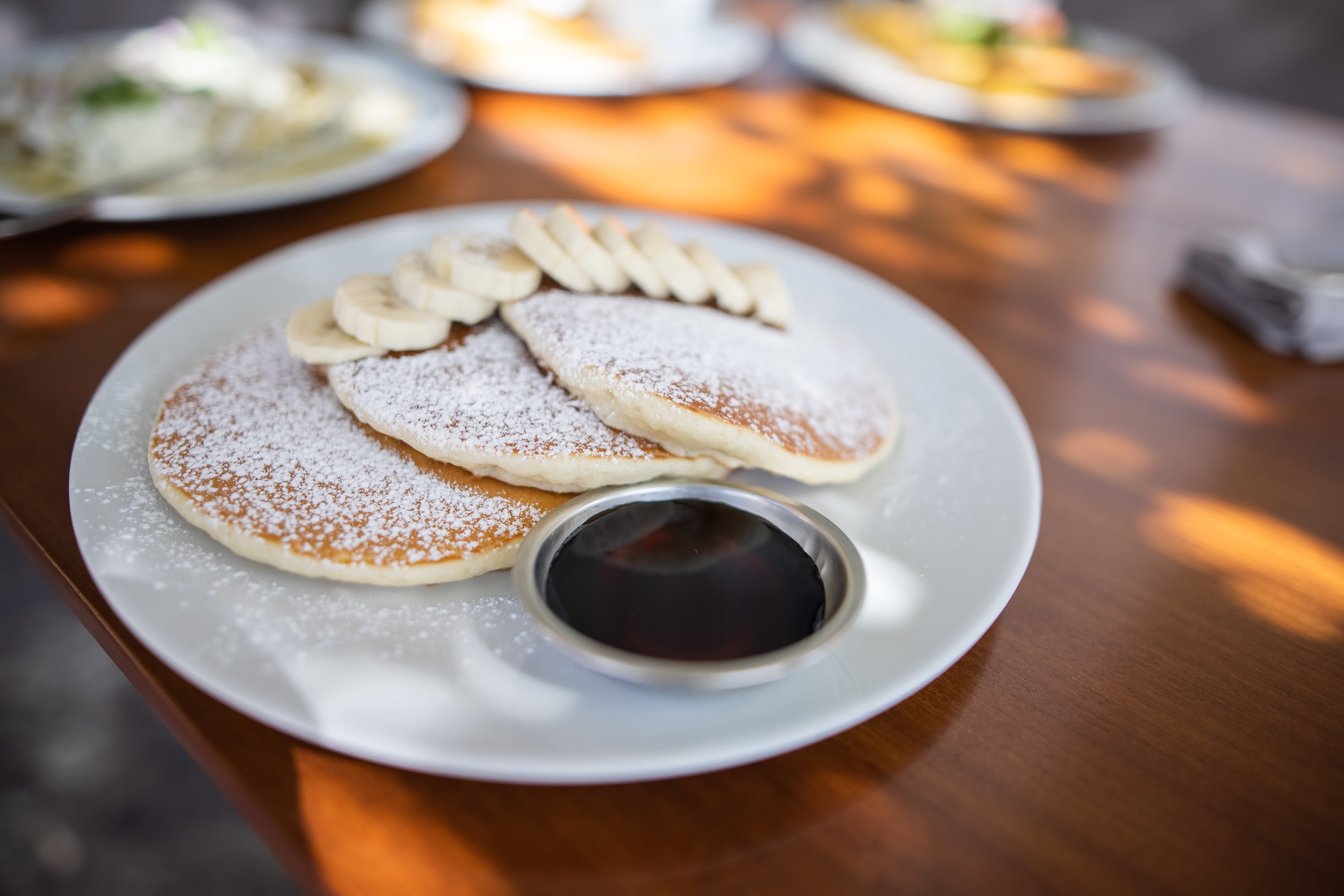 Pancakes with Bananas and Syrup on Wooden Table