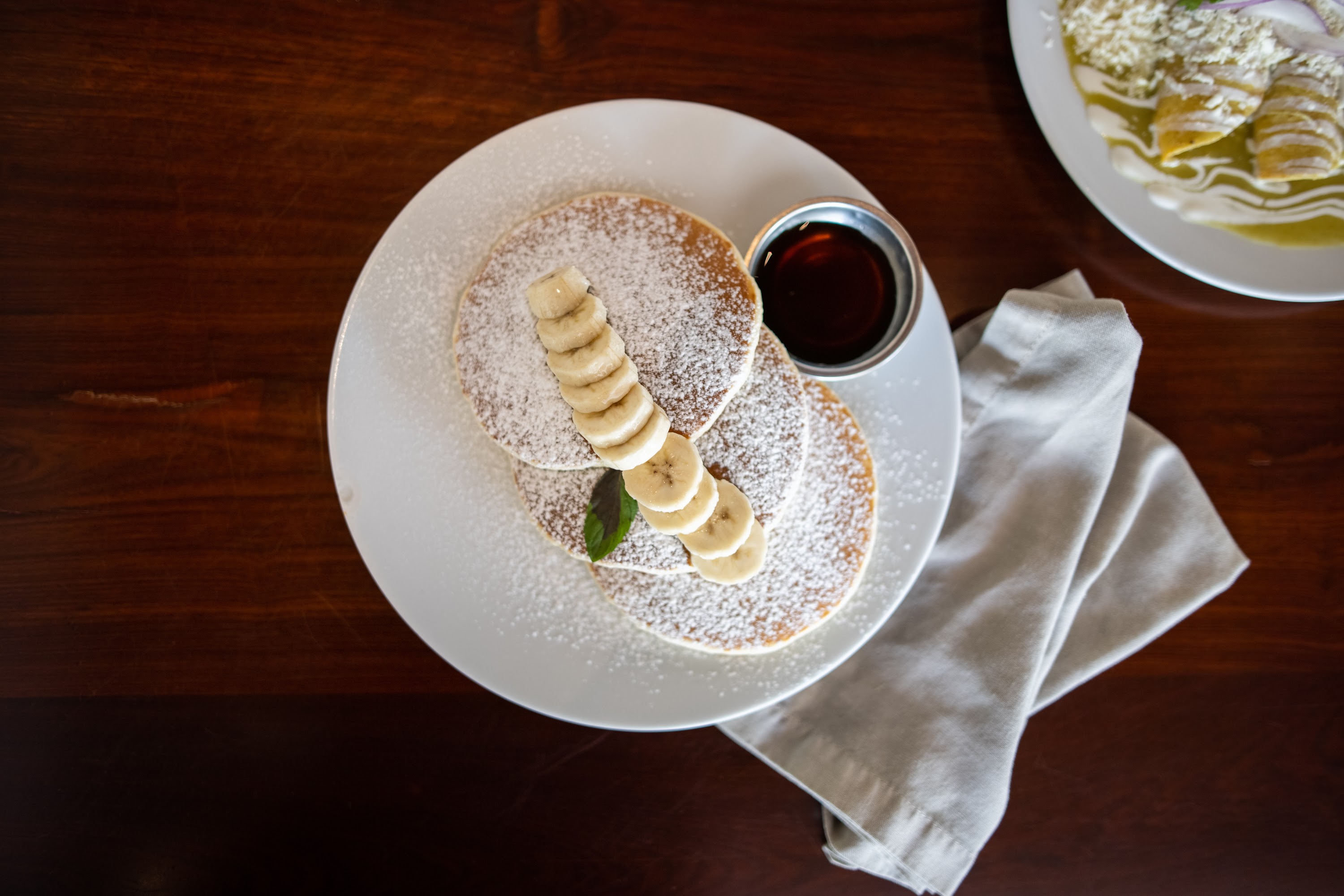 Stack of Banana Pancakes with Syrup and Powdered Sugar