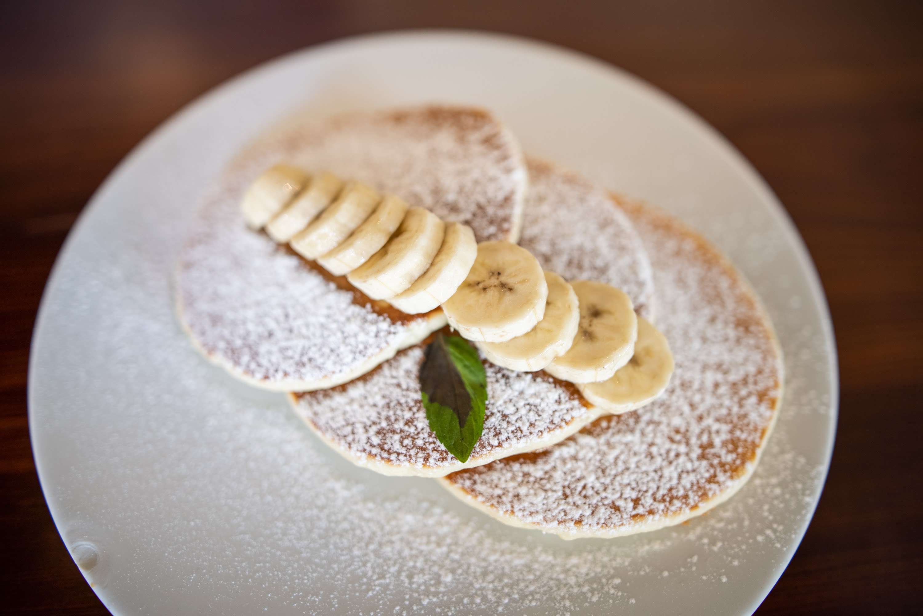 Stack of Banana Pancakes with Powdered Sugar and Mint