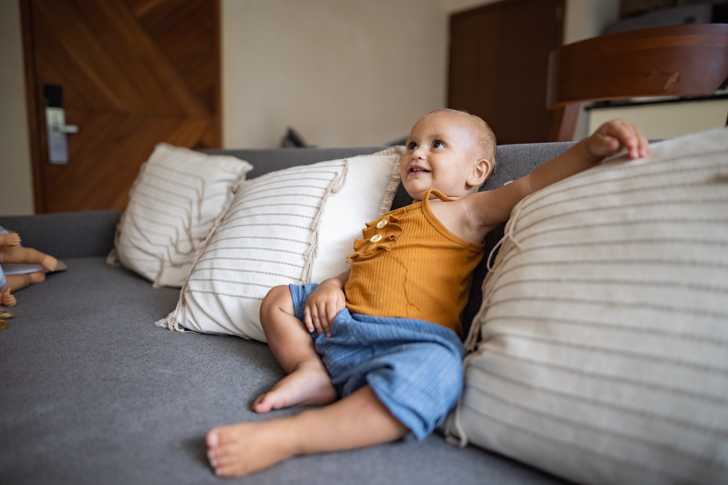 Smiling Baby Sitting on Gray Couch