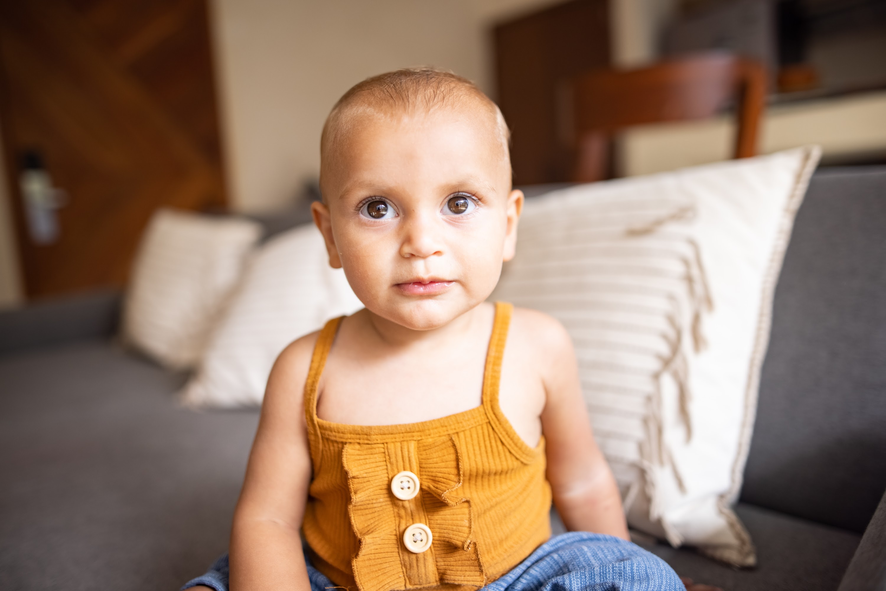 Baby in Yellow Top Sitting on Couch