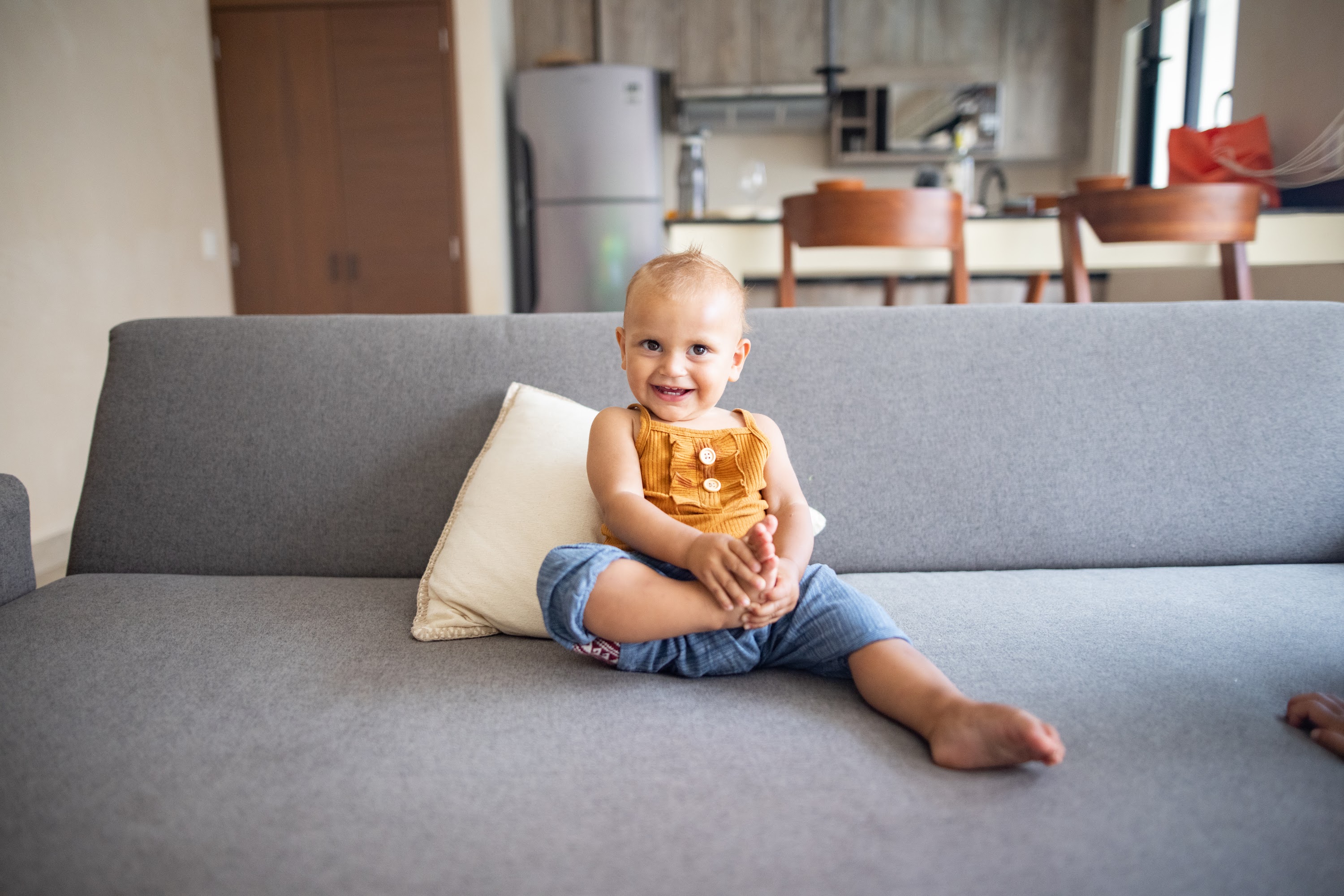Smiling Baby Sitting on Gray Couch in Modern Living Room