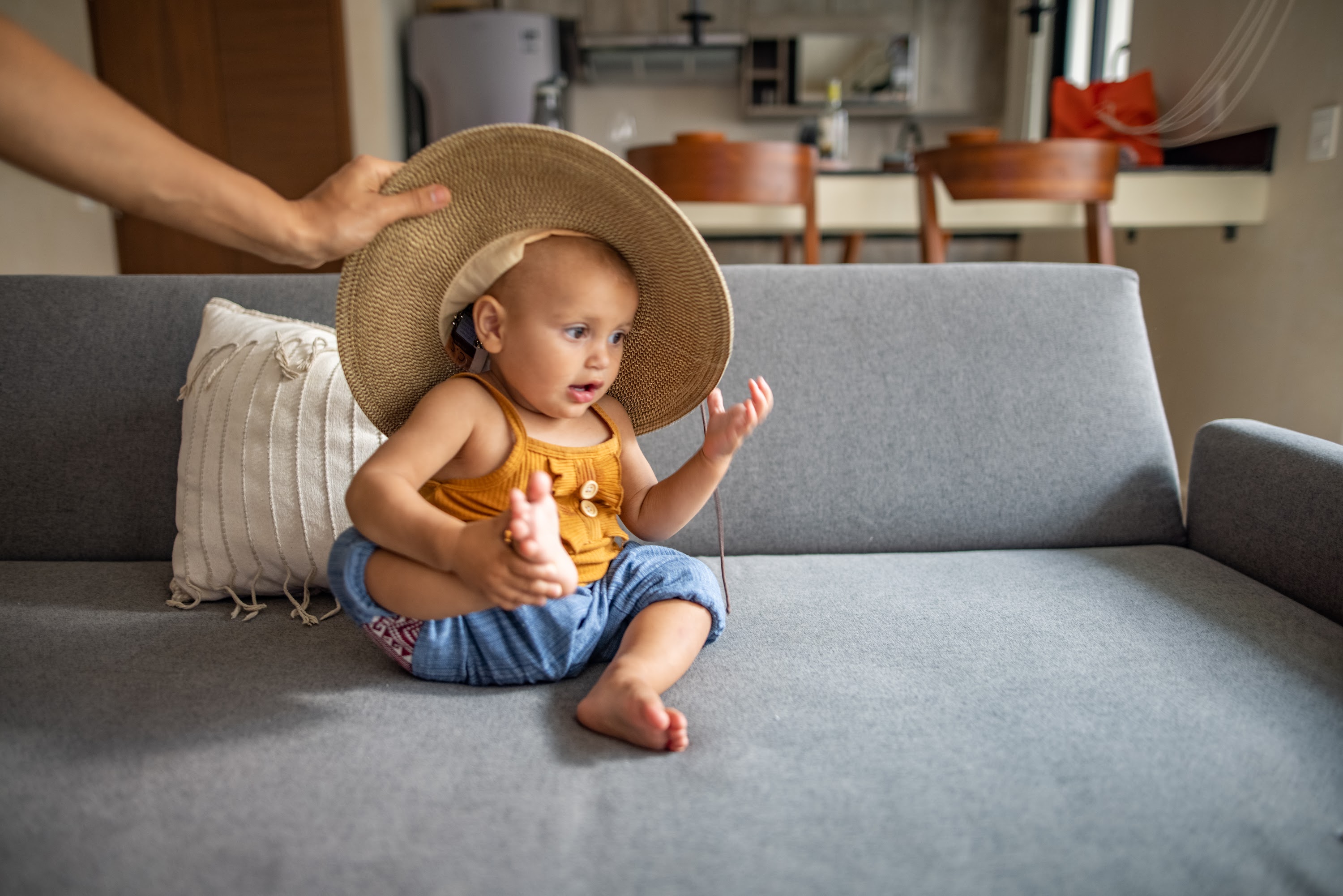 Baby Wearing a Large Straw Hat on Couch