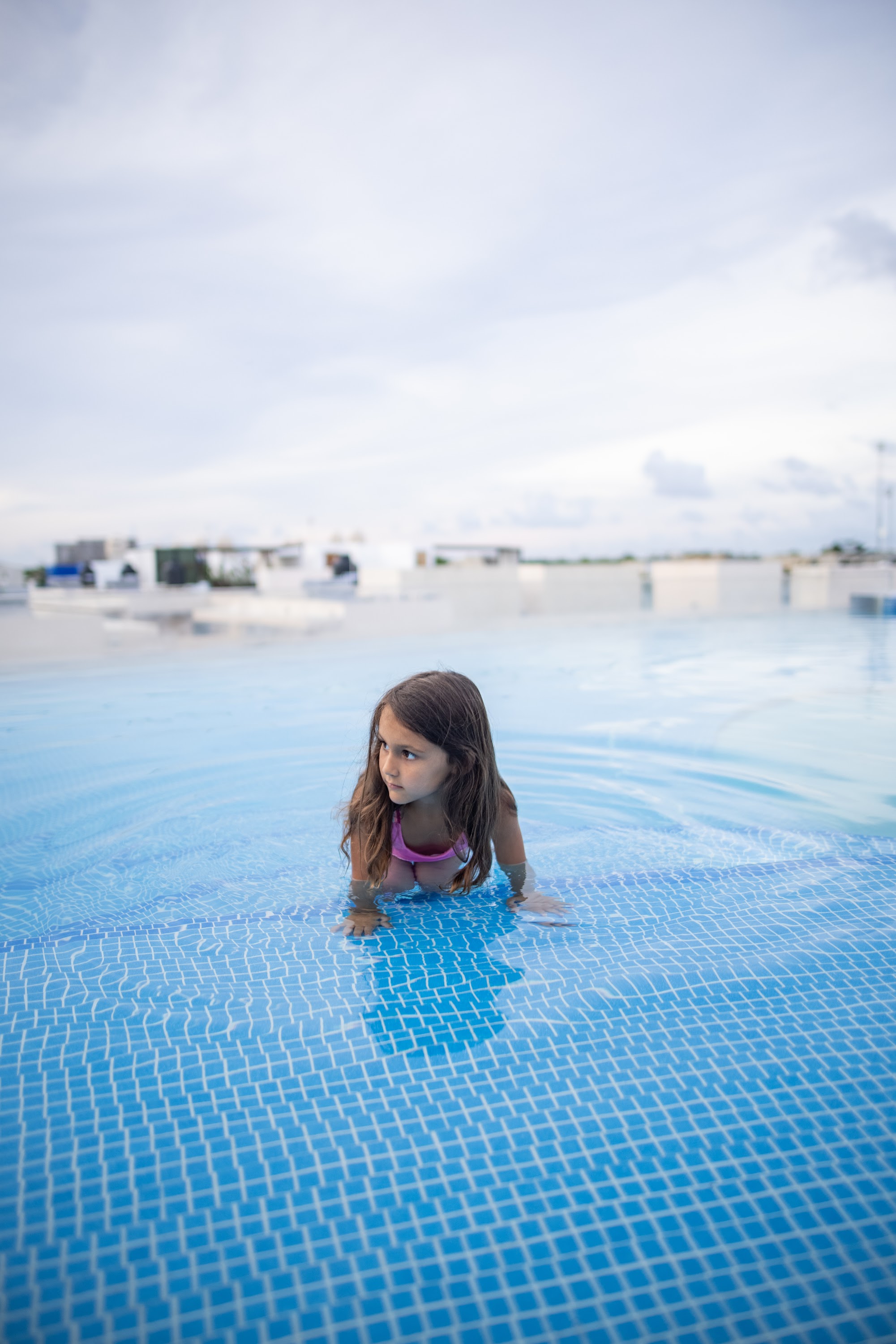 Young Girl at the Edge of a Blue-Tiled Pool