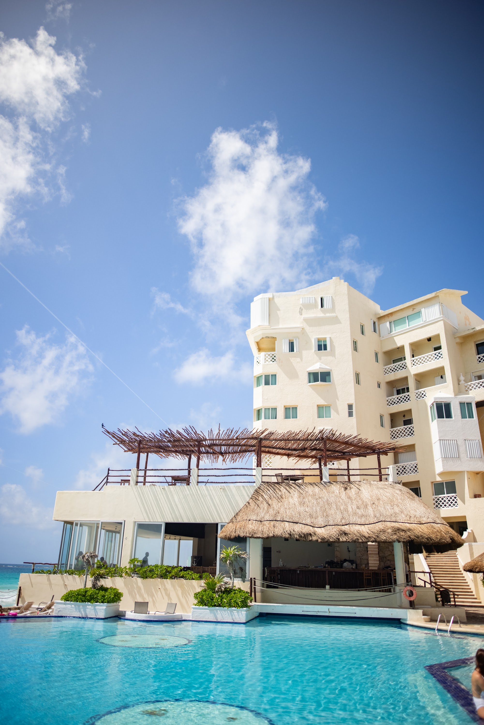 Beachside Resort Pool with Thatched Roof and Modern Building