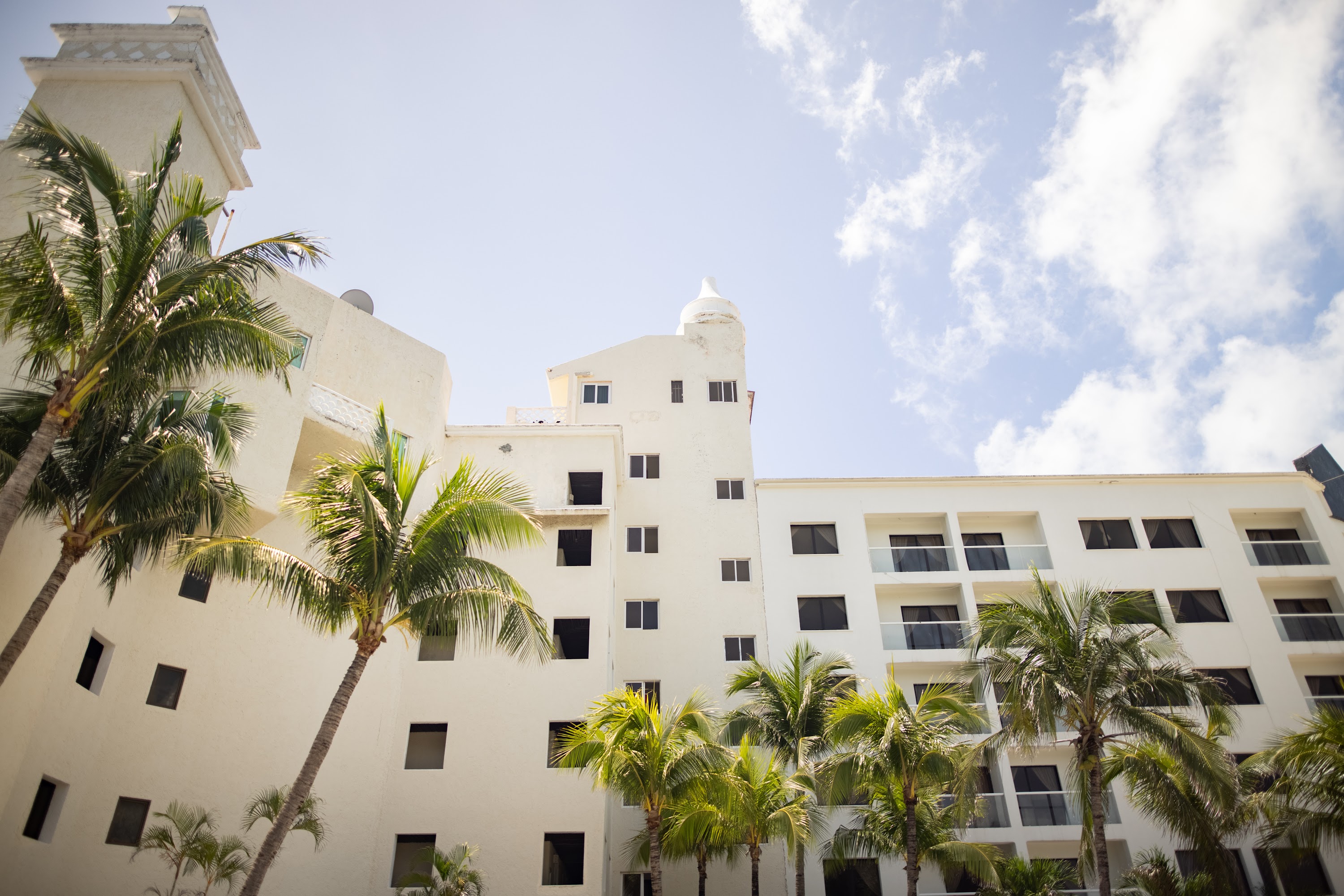 White Resort Building with Palm Trees Under Blue Sky