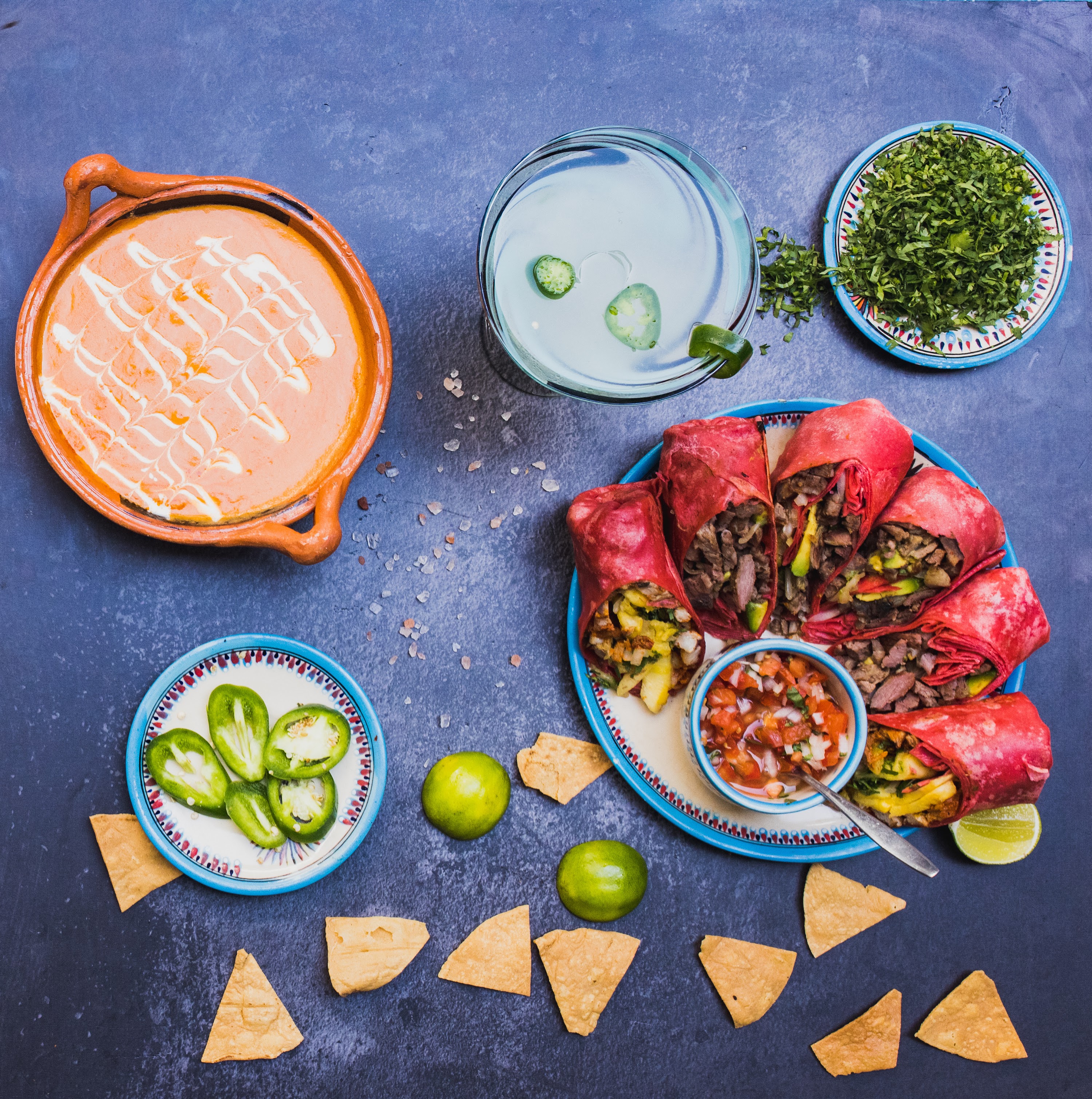 Mexican-inspired meal with burritos, soup, and garnishes