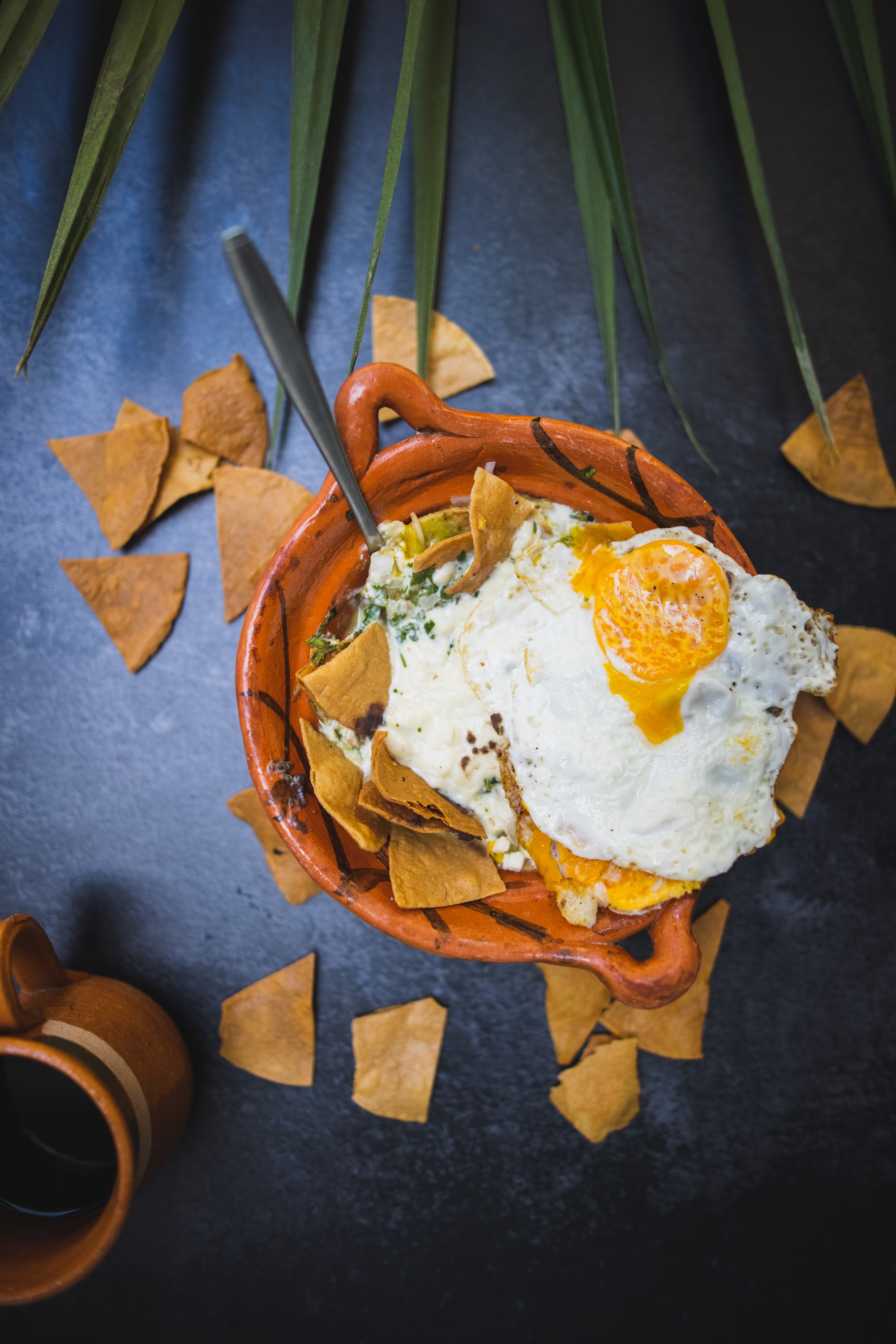 Overhead shot of chilaquiles with fried egg in terracotta bowl